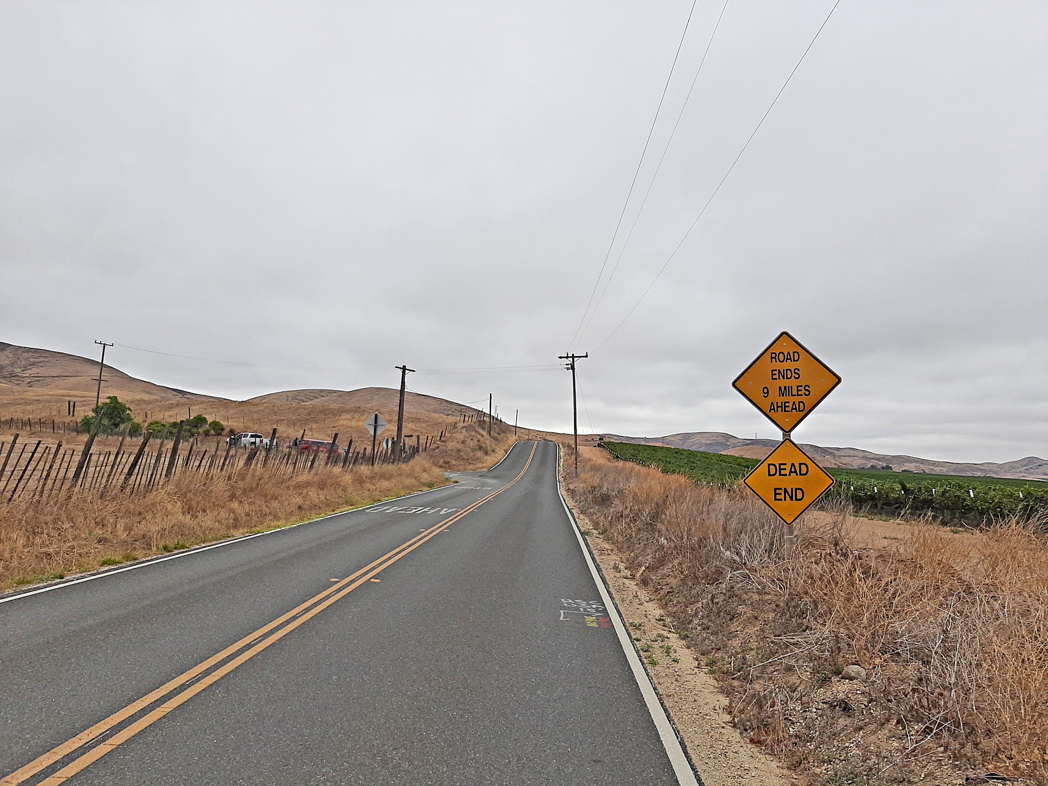 Cycling Pinnacles National Park, California - two-lane highway road surrounded by tall brown grass, road sign says "Road Ends 9 Miles Ahead, Dead End"
