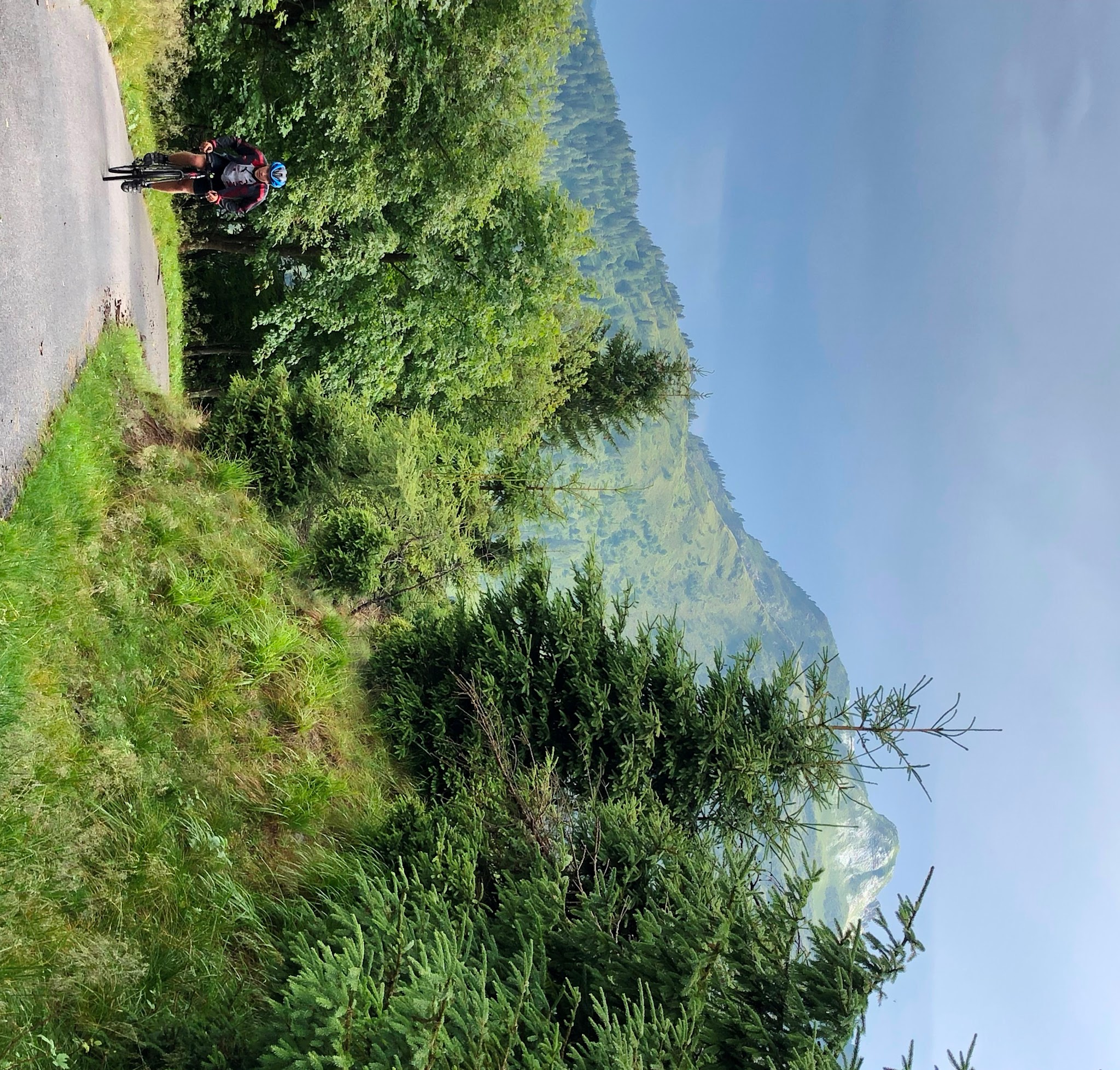 Bicycle ride on Passo della Forcella - cyclist coming up steep road with Italian Alps in background