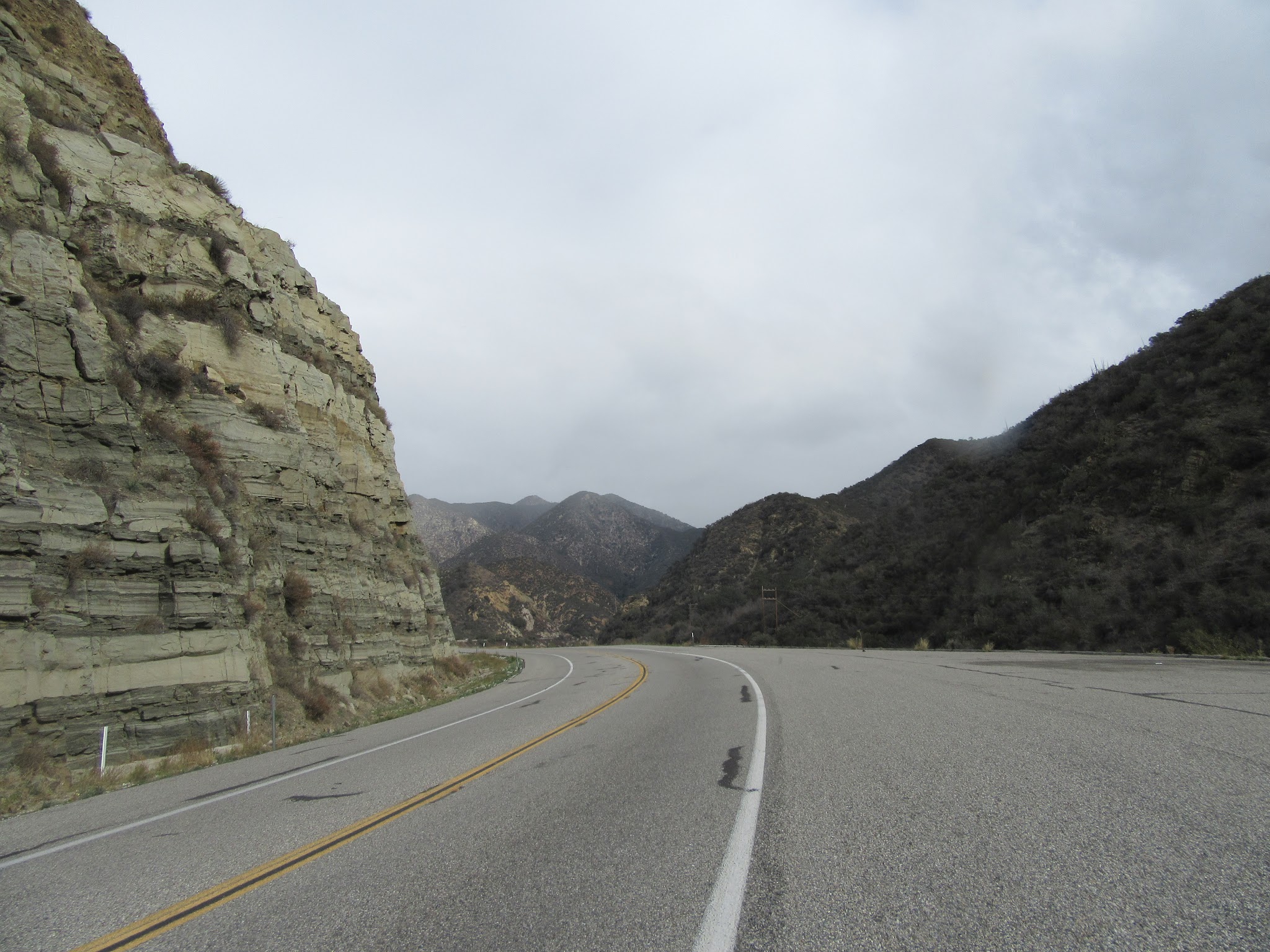 Two lane highway roadway with large stone wall