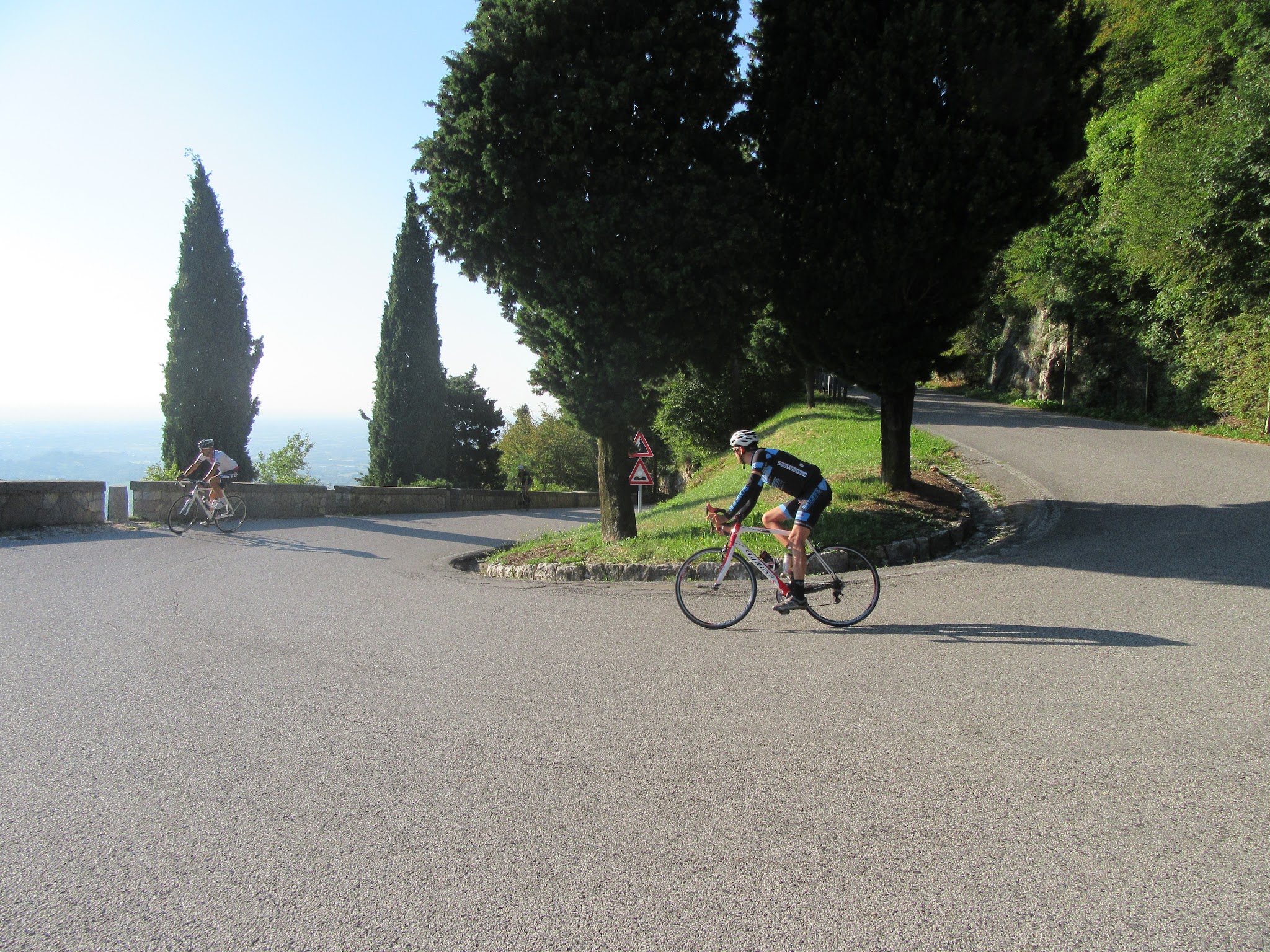 Climbing by bike Monte Grappa from Romano d'Ezzilino - tornante, cyclists and roadway