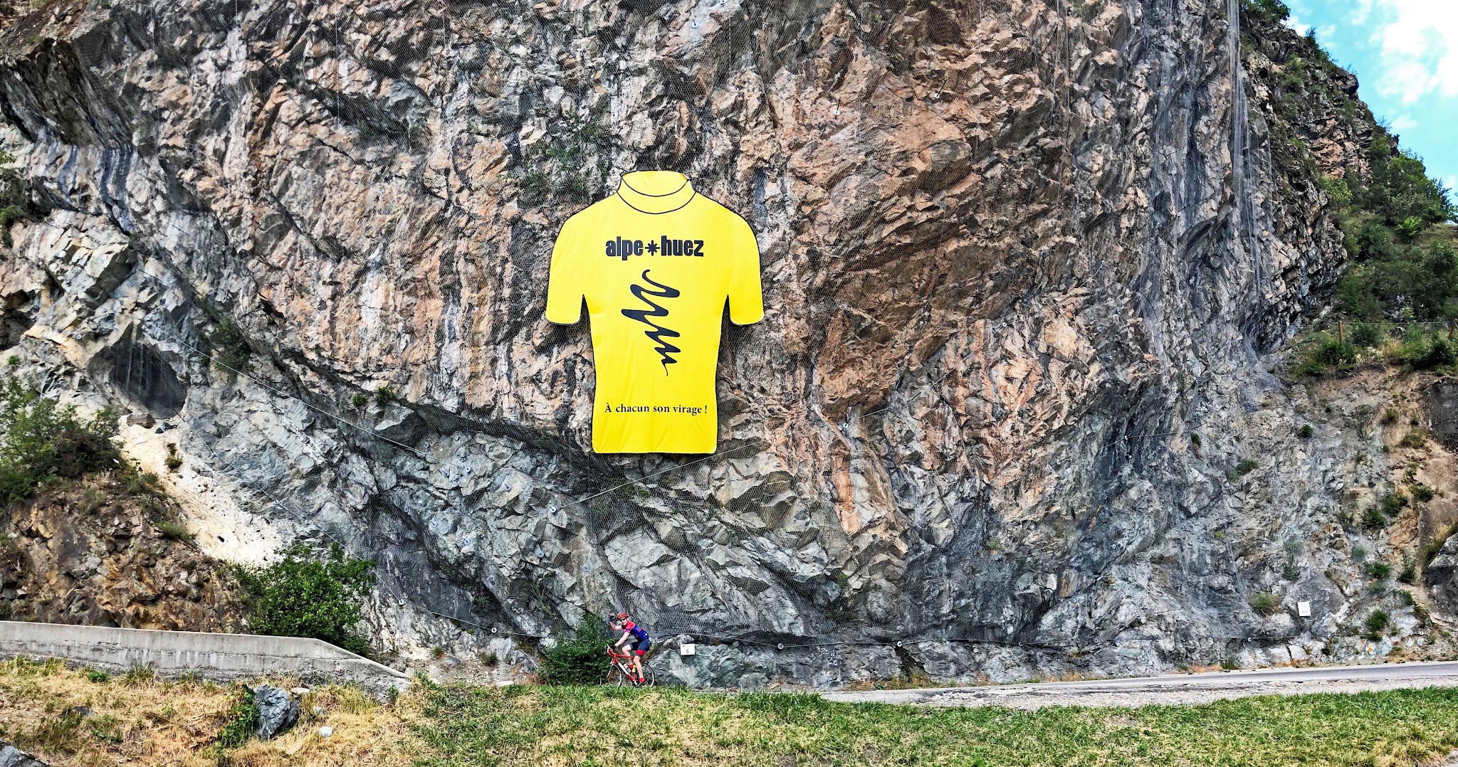 Cycling Alpe d'Huez - large yellow jersey sign on rock wall roadside