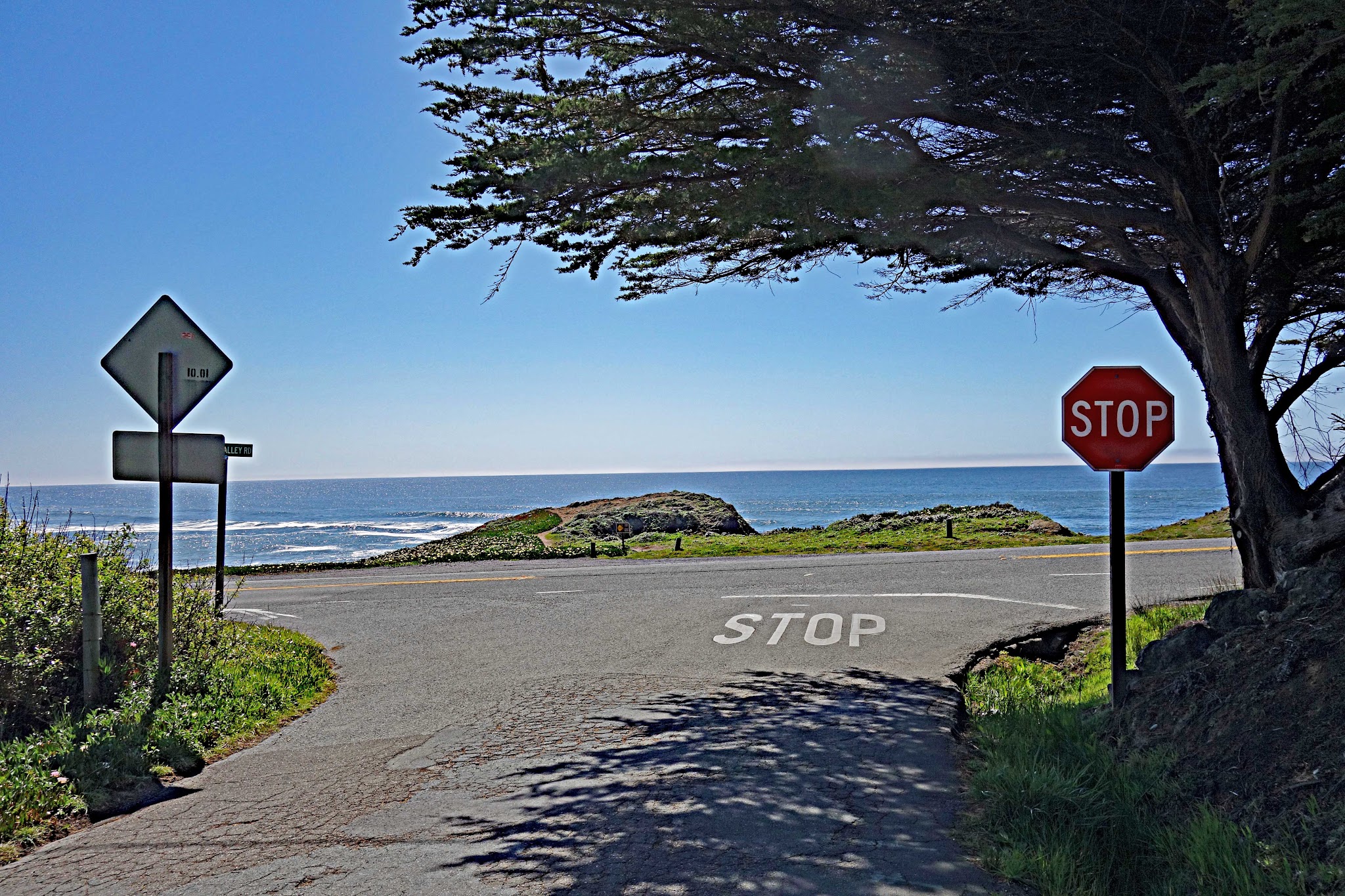 Start of the Coleman Valley Road climb by bike view west to Pacific Ocean, Hwy 1 and road signs. 