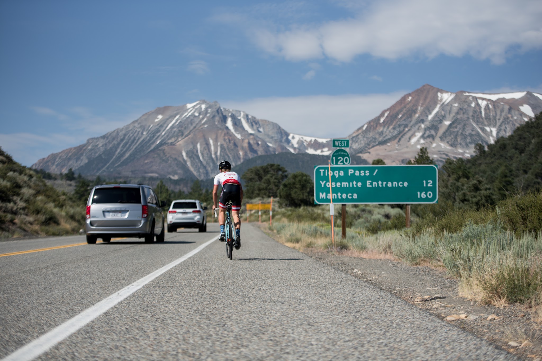 Cycling Tioga Pass - beginning of climb - cyclist on bike with roadway sign; hwy 120 sign