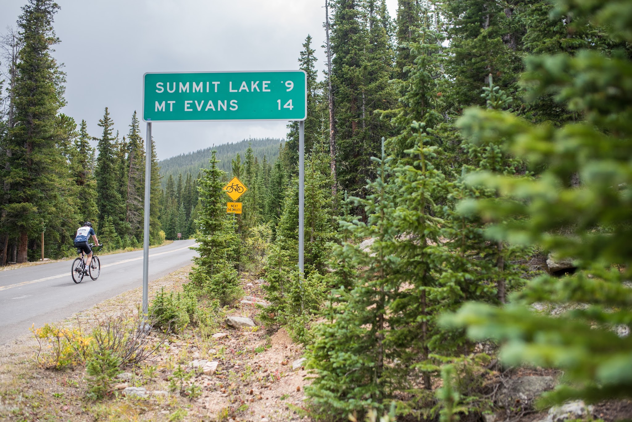 Cycling past road sign on Mt Evans Road Rocky Mountains