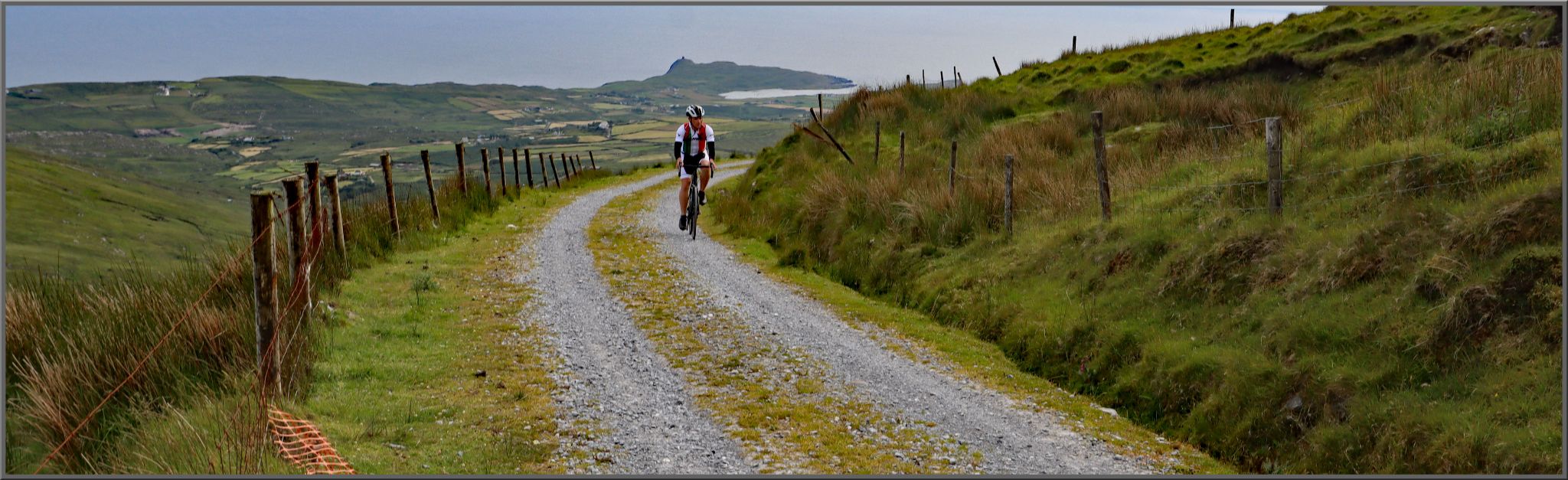 PJAMM Cyclist rides on gravel roadway surrounded by grassland