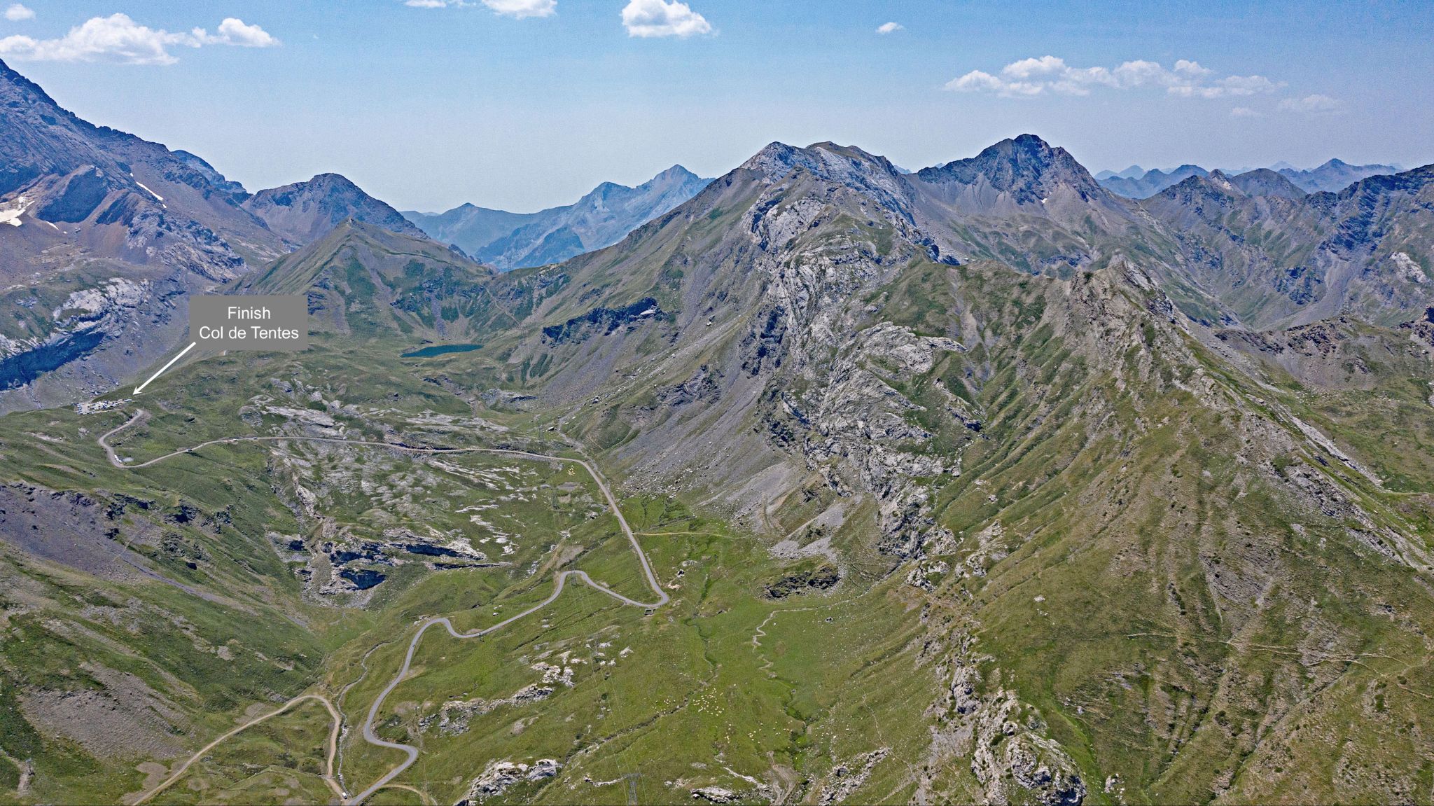 panoramic view shows Col de Tentes upper left of photo, roadway snaking up to finish