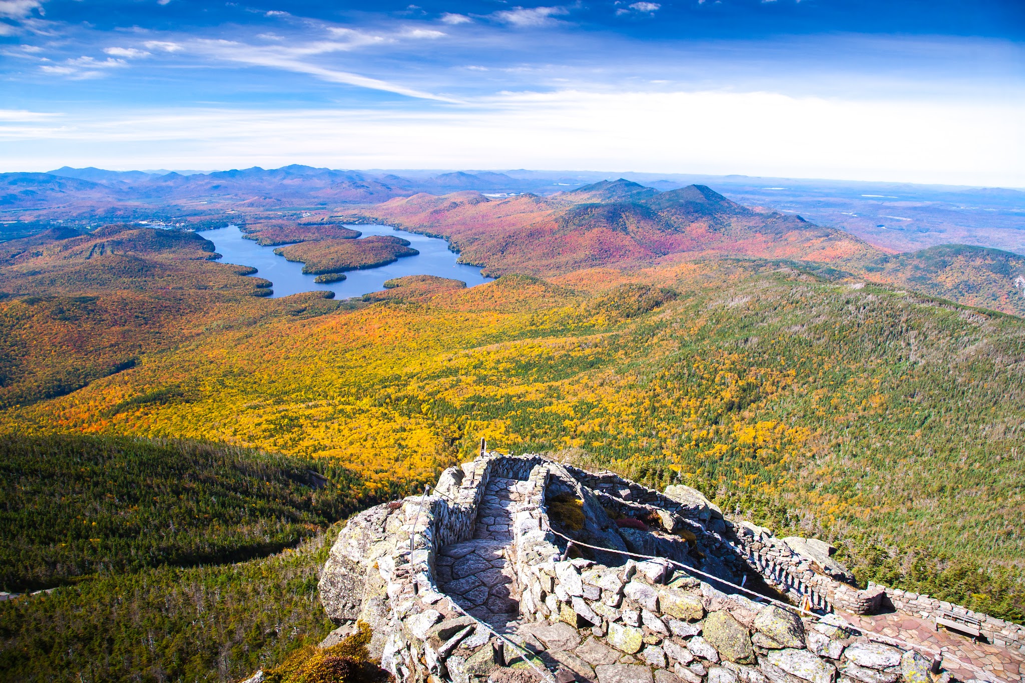 Cycling Whiteface Mountain Cycling Whiteface Mountain - view from above with rock wall-lined staircase in foreground and green and golden hillsides in center, with "U" shaped lake in background surrounded by reddish hillsides