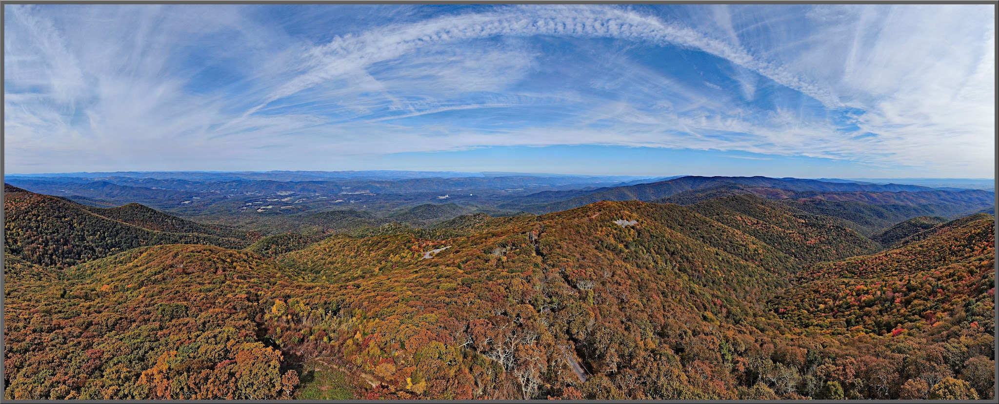 Cycling Reddish Knob, Virginia - aerial panoramic view of hillsides covered in bright fall foliage, bright blue sky
