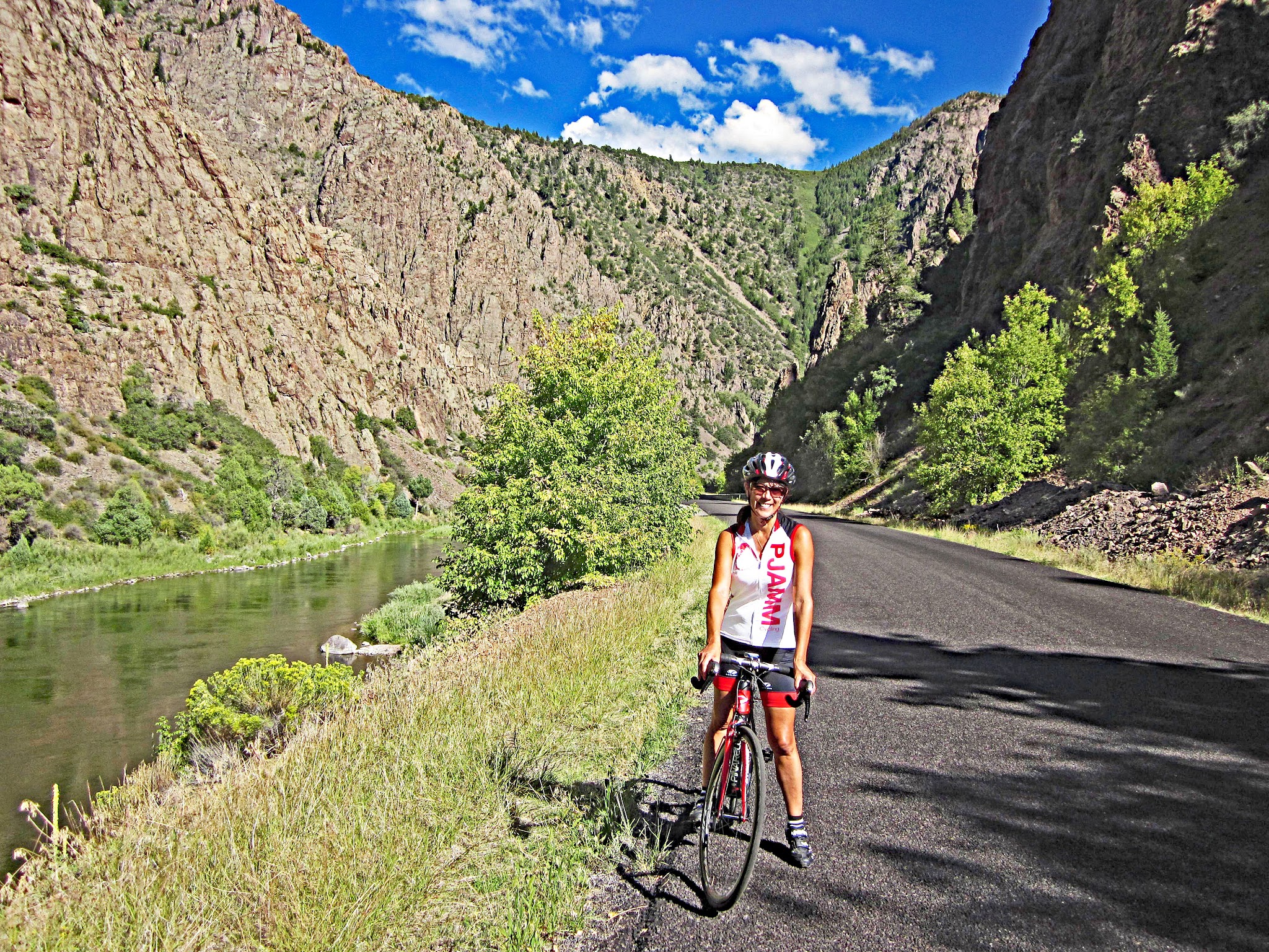 Cycling East Portal, Colorado - cyclist wearing PJAMM Cycling jersey parked on roadside next to creek surrounded by grey rocky hillsides