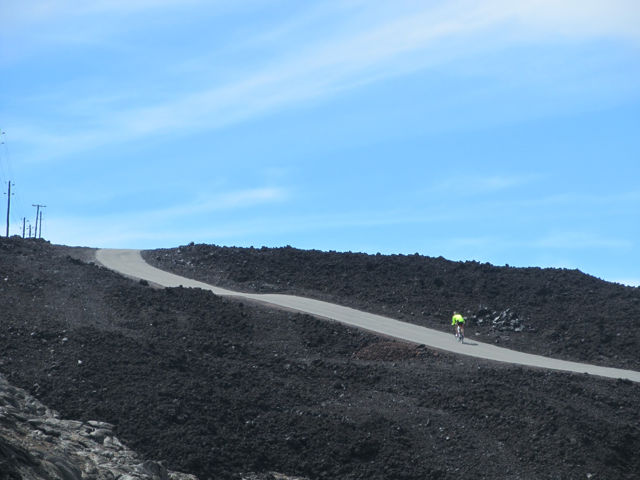 Climbing by bike Mauna Loa Volcano - cyclist climbing steep section of Mauna Loa Observatory Road