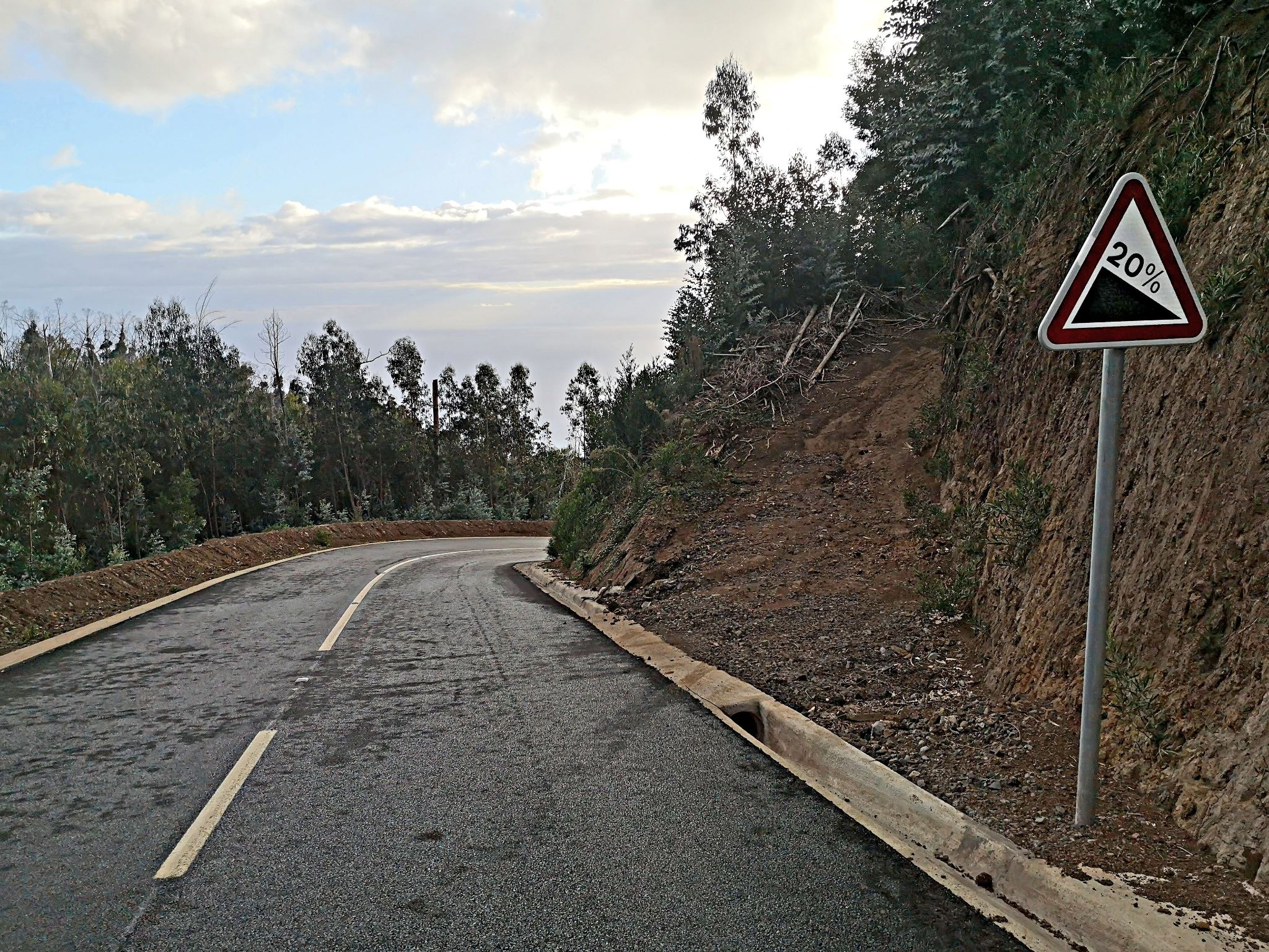 view looking down two-lane roadway, road sign reads 20% grade