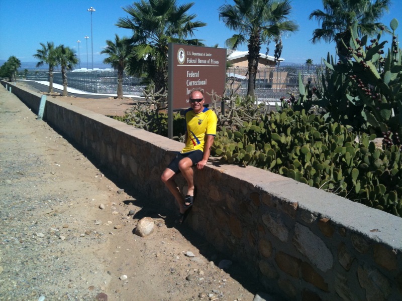 Cycling Mt. Graham, Arizona - John Johnson sits on retaining wall next to the Safford Federal Correctional Institution 