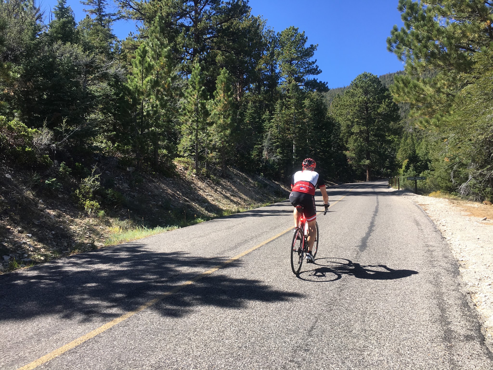 Bicycle climb up Wheeler Peak - cyclist on road with snow covered peak in background