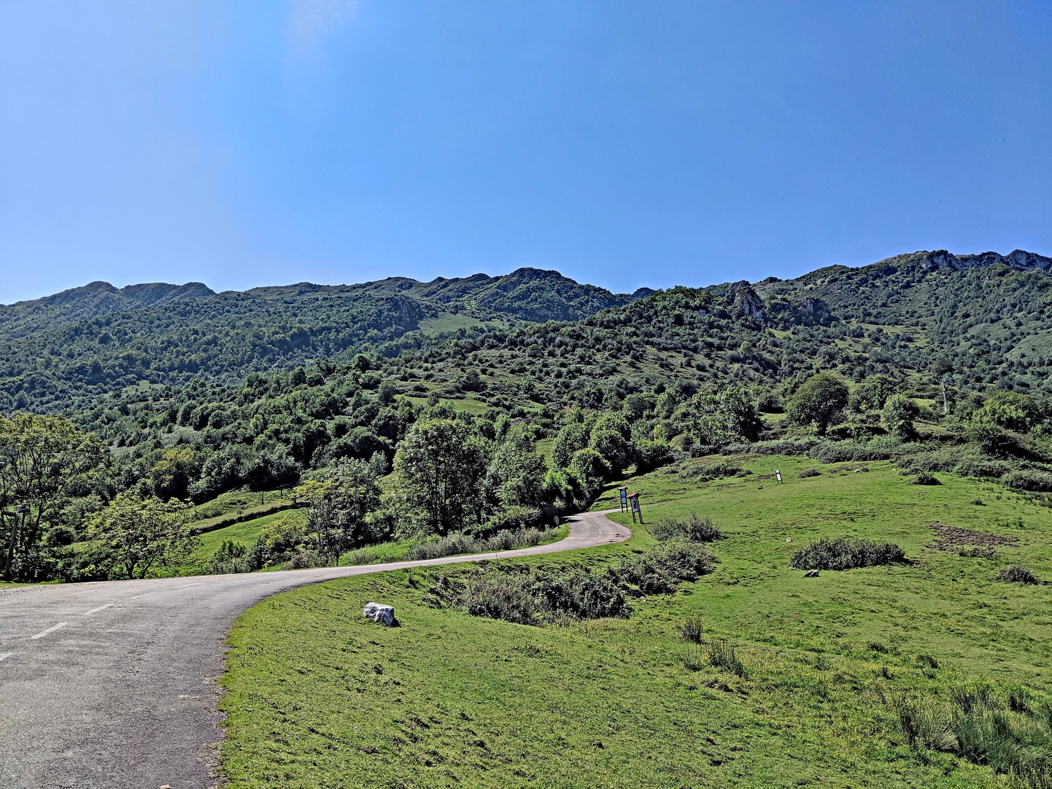 Cycling Alto de l'Angliru, Spain - at Kilometer 6.7 of climb, two-lane roadway is smooth before pitching up through green hillsides