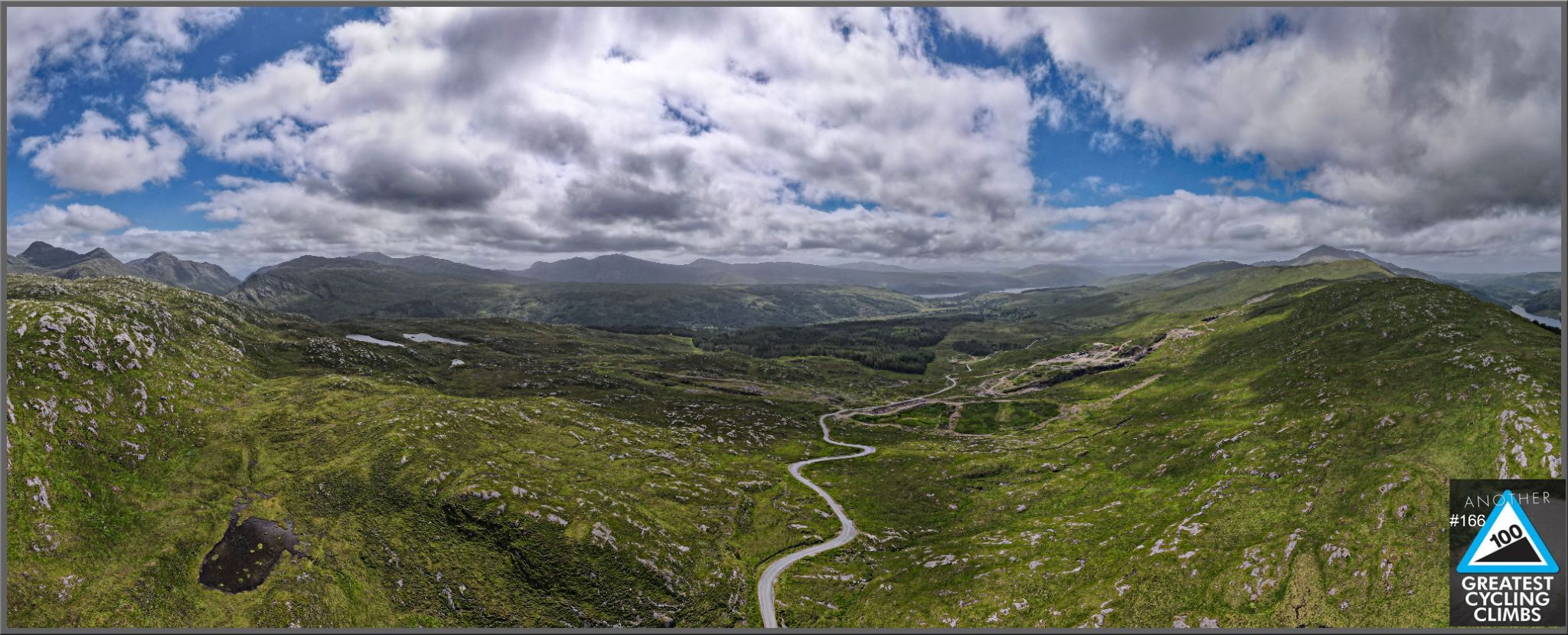 panoramic view looking down over valley, roadway snaking through center of valley, green hillsides