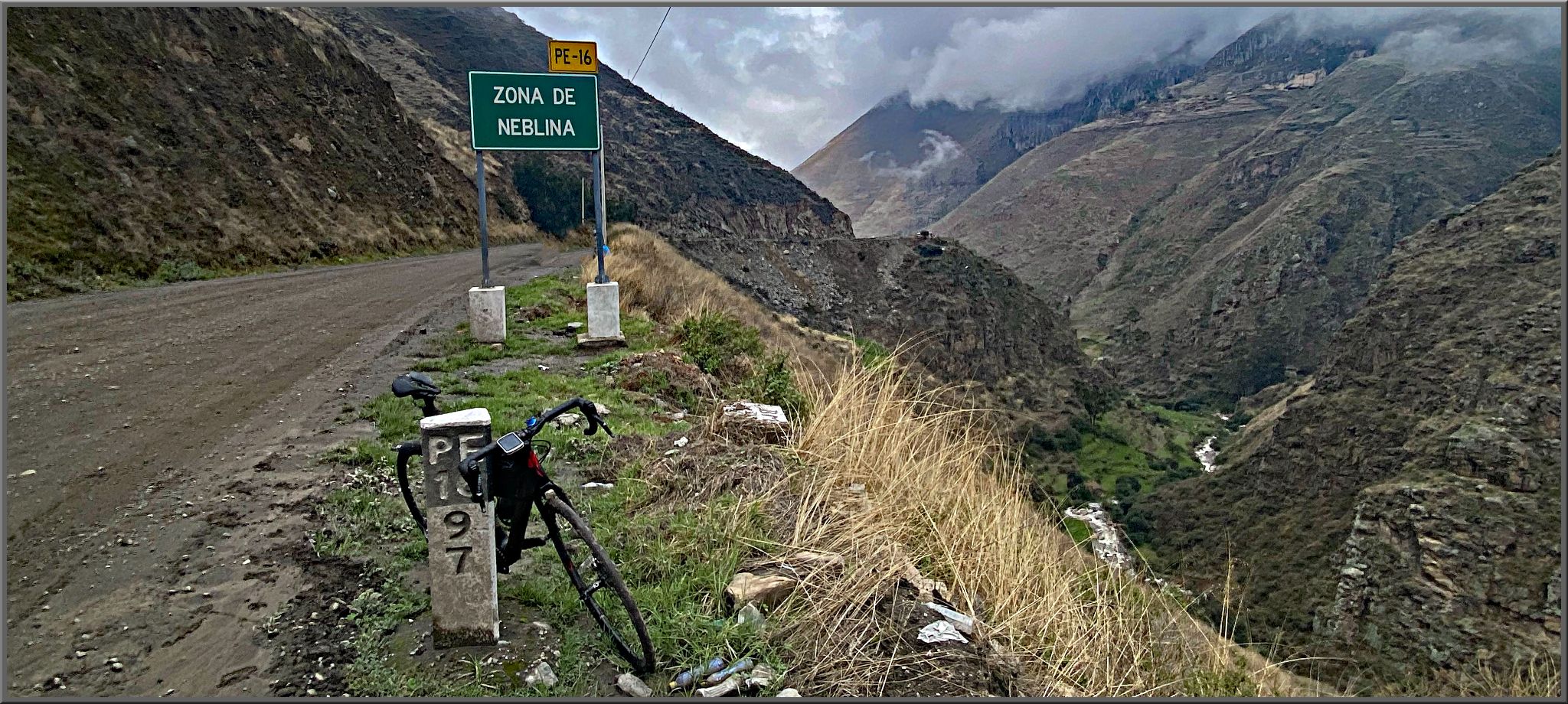 Cycling Conococha, Peru - bike parked on mountain roadside next to road sign for Zona de Neblina
