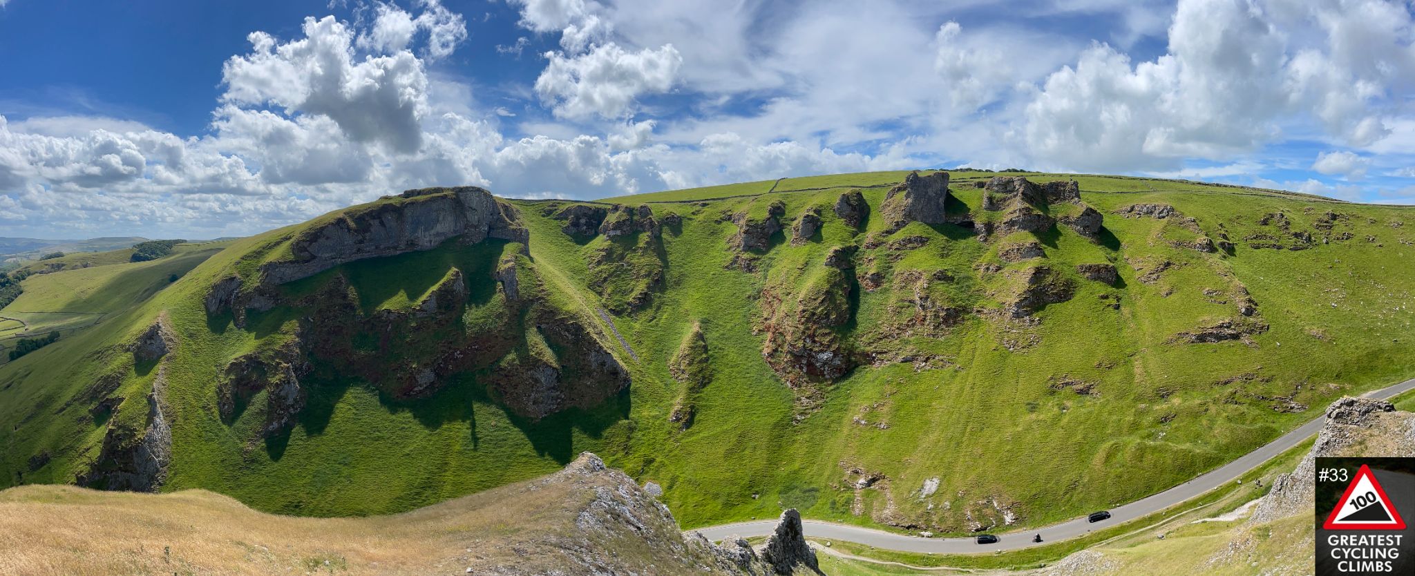 panoramic view of Winnats Pass, green hills with stone outcropping, blue sky