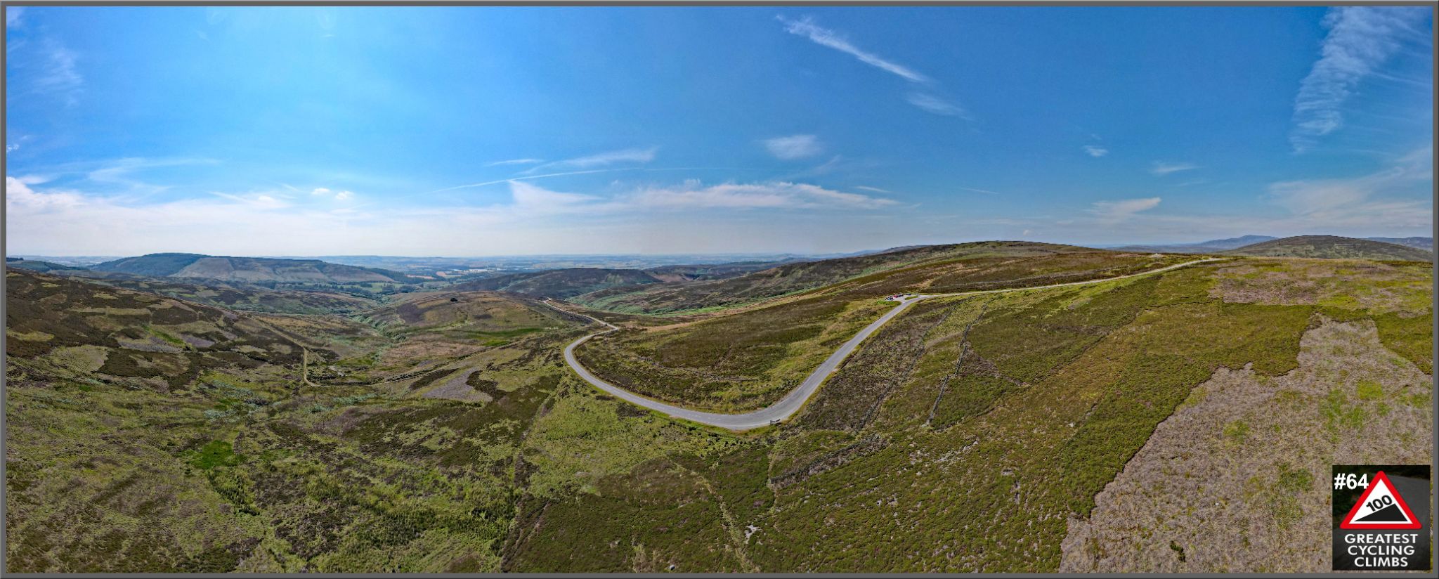 panoramic view of the Cairn O'Mount climb, roadway switchbacking up hillside, bright blue sky