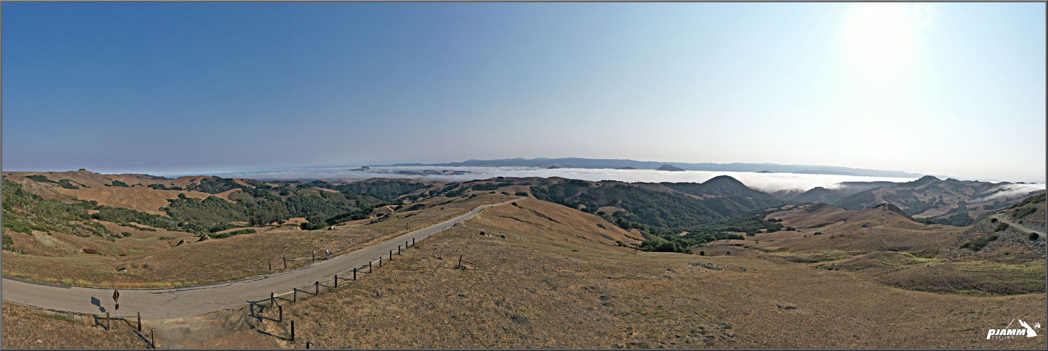 panoramic view looking down along one-lane country road surrounded by dry grassland going out toward the ocean and coastline, Prefumo Canyon, San Luis Obispo, California