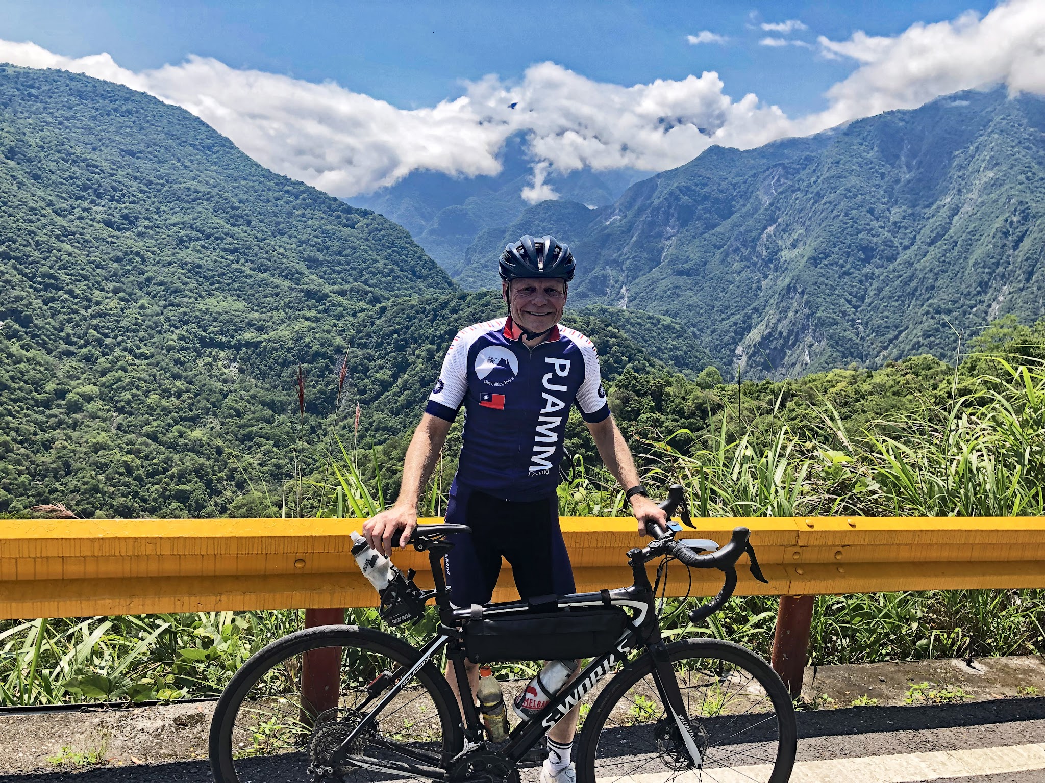 Cycling Wuling Pass East - PJAMM Cycling - Mitch Reid, John Johnson with bikes at summit sign.