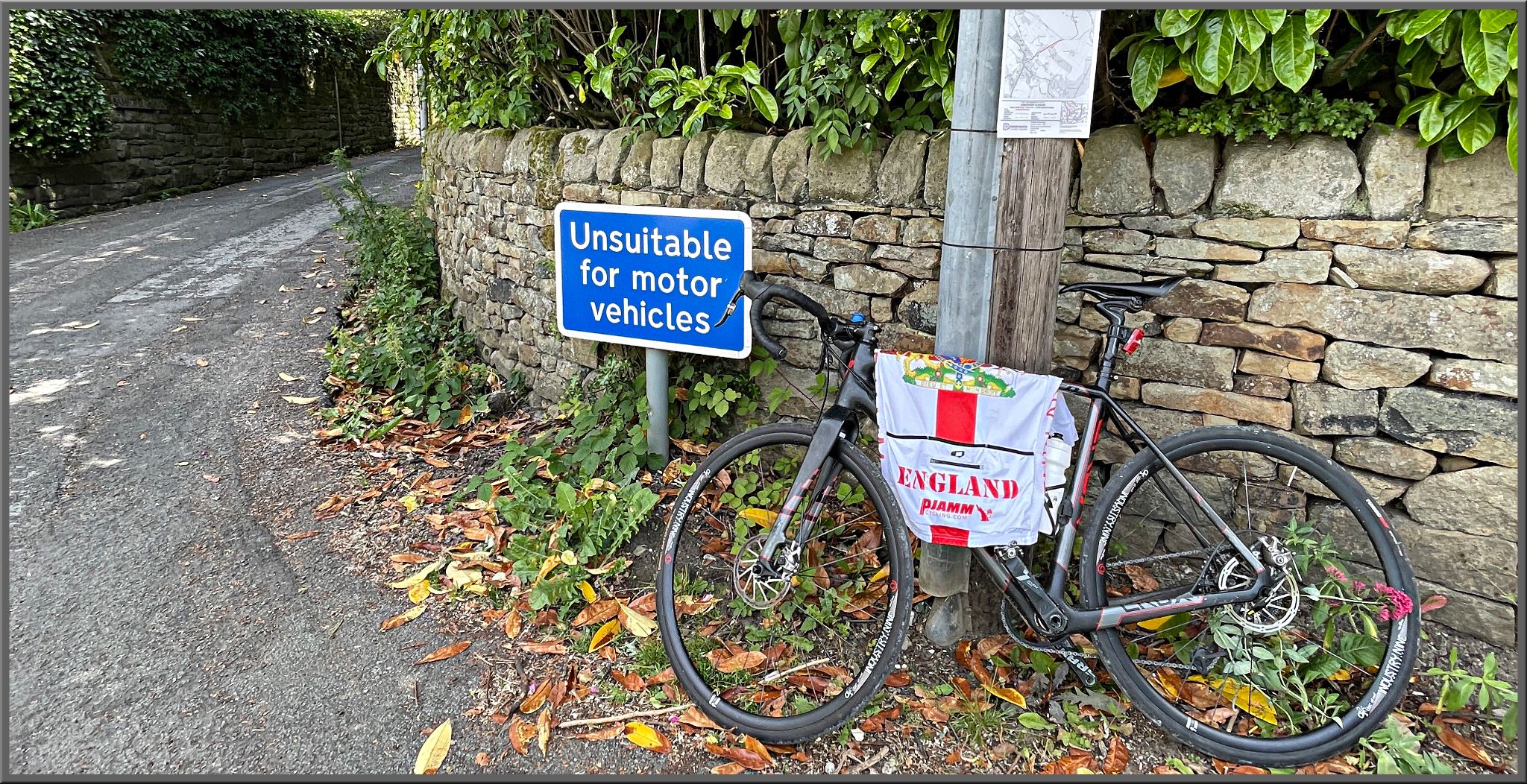 Cycling Bamford Clough bike parked next to sign reading "unsuitable for motor vehicles"