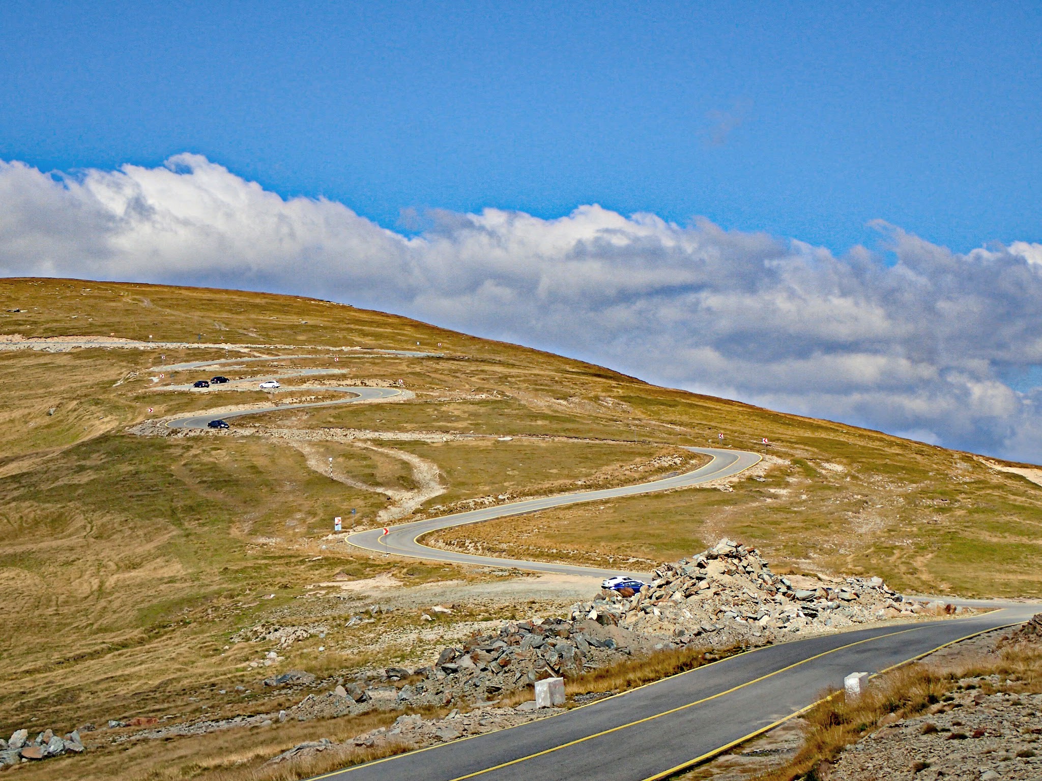 Cycling Transalpina North, Romania - two-lane highway roadway in pristine condition snaking its way up the mountainside covered in green grass