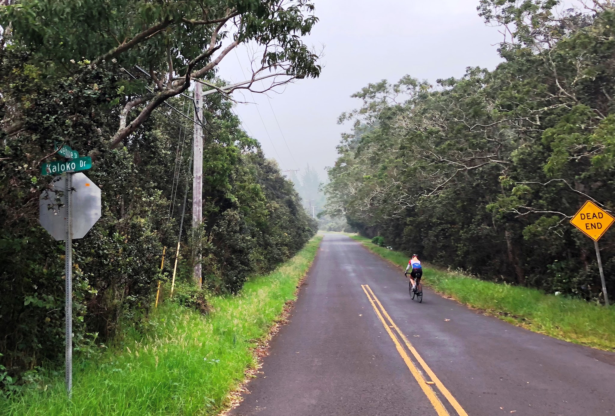 Huelue Street sign with cyclist climbing volcano on Kaloko Drive bike climb.