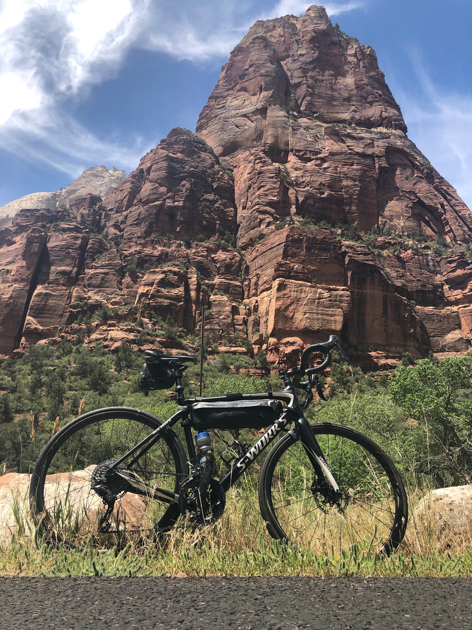 Zion Canyon Scenic Drive Cycling Zion Canyon Scenic Drive - bike leaning against sign on road with Angels Landing in background.