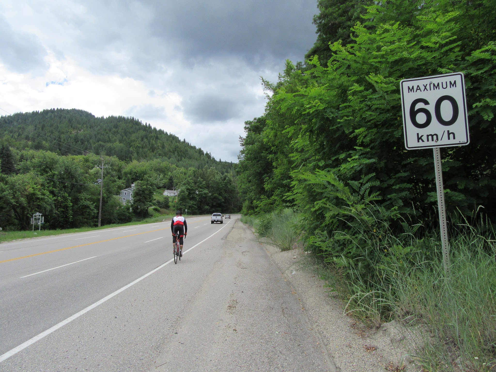 Bike climbStrawberry Pass, BC, CAN - cyclist riding past 60 km/h sign 
