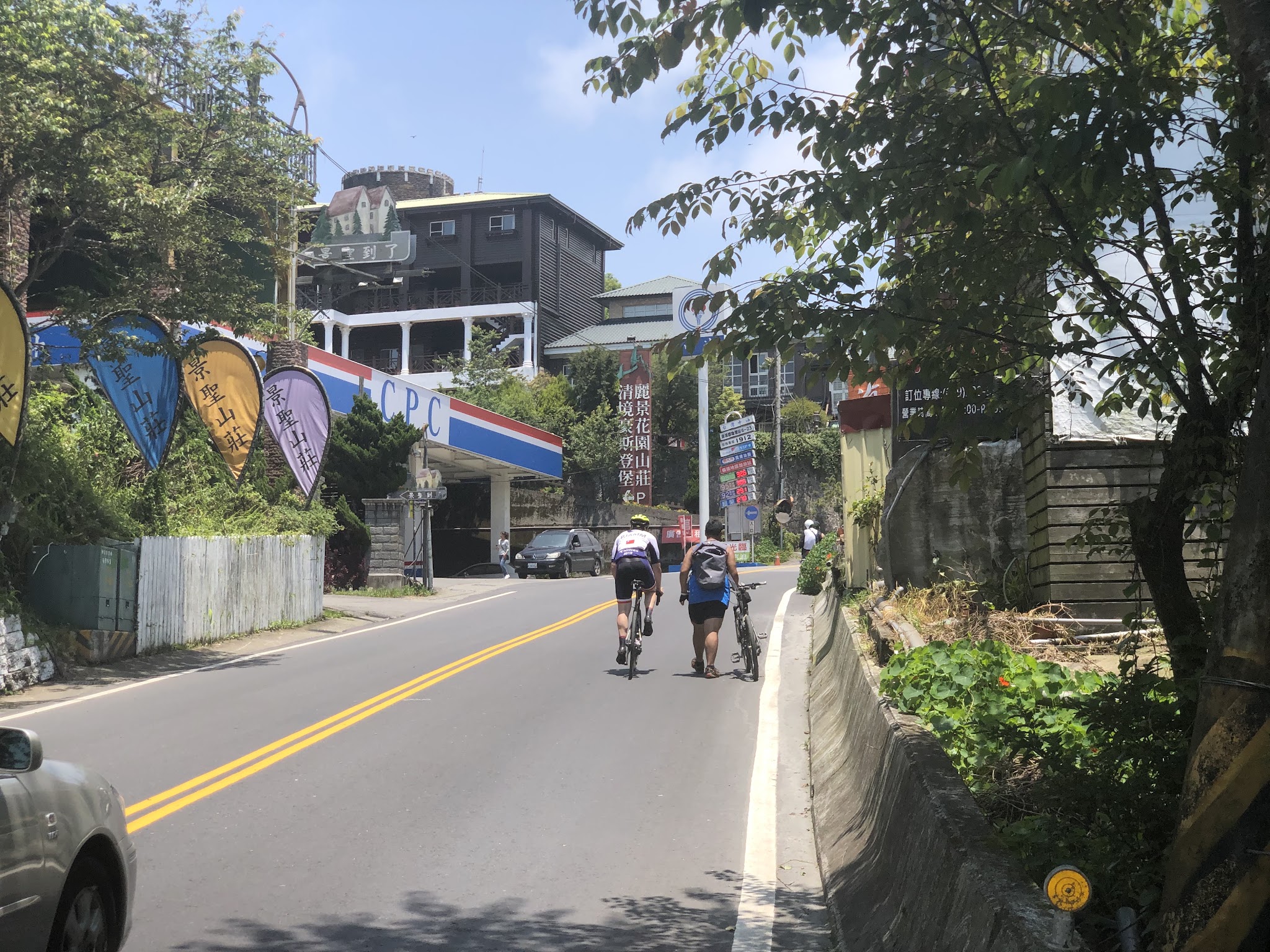 Climbing Wuling Pass West by bike - cyclist passing cyclist walking bike on road