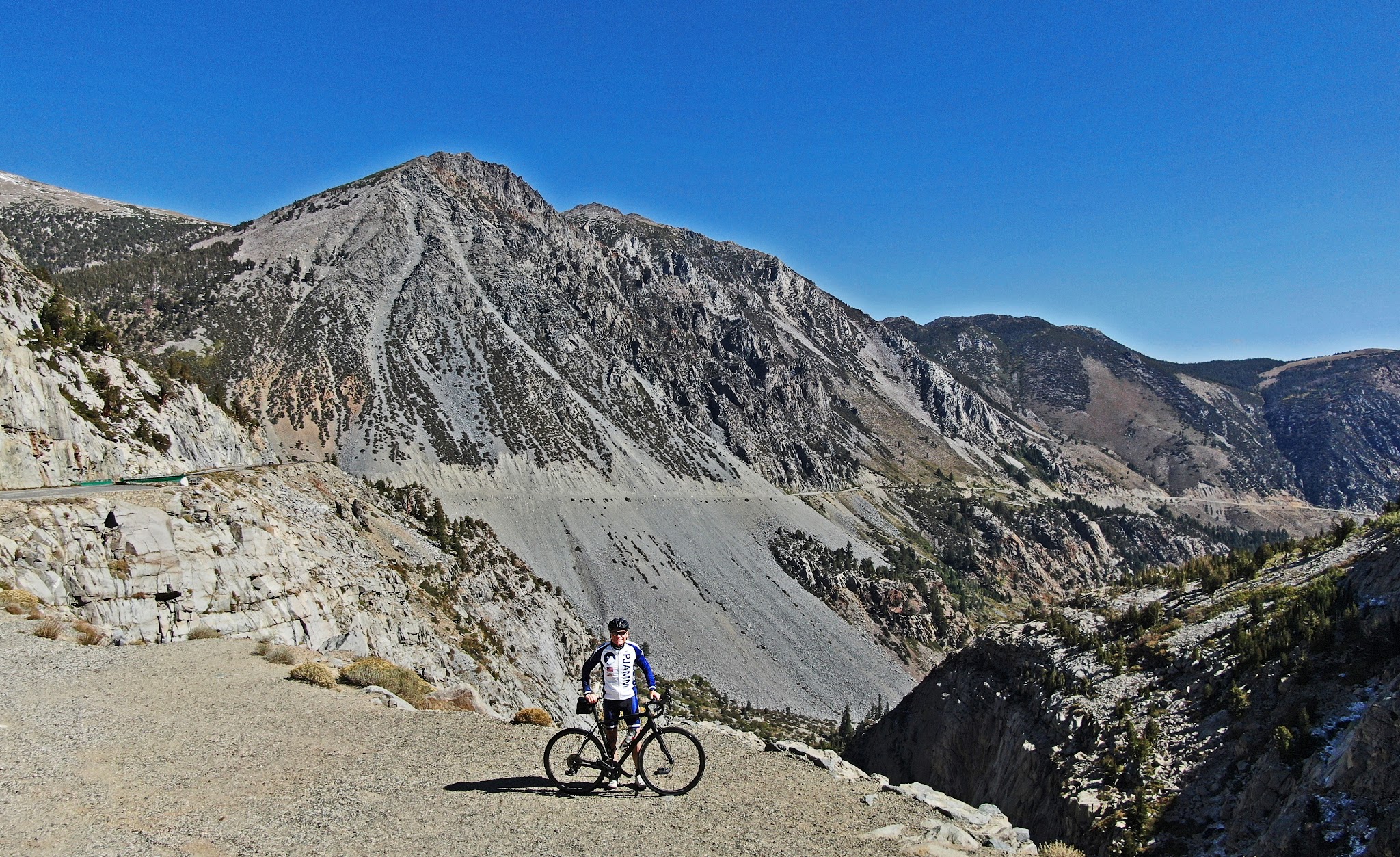 PJAMM Cyclist stands with bike on mountainside, Tioga Pass, amazing rock formations