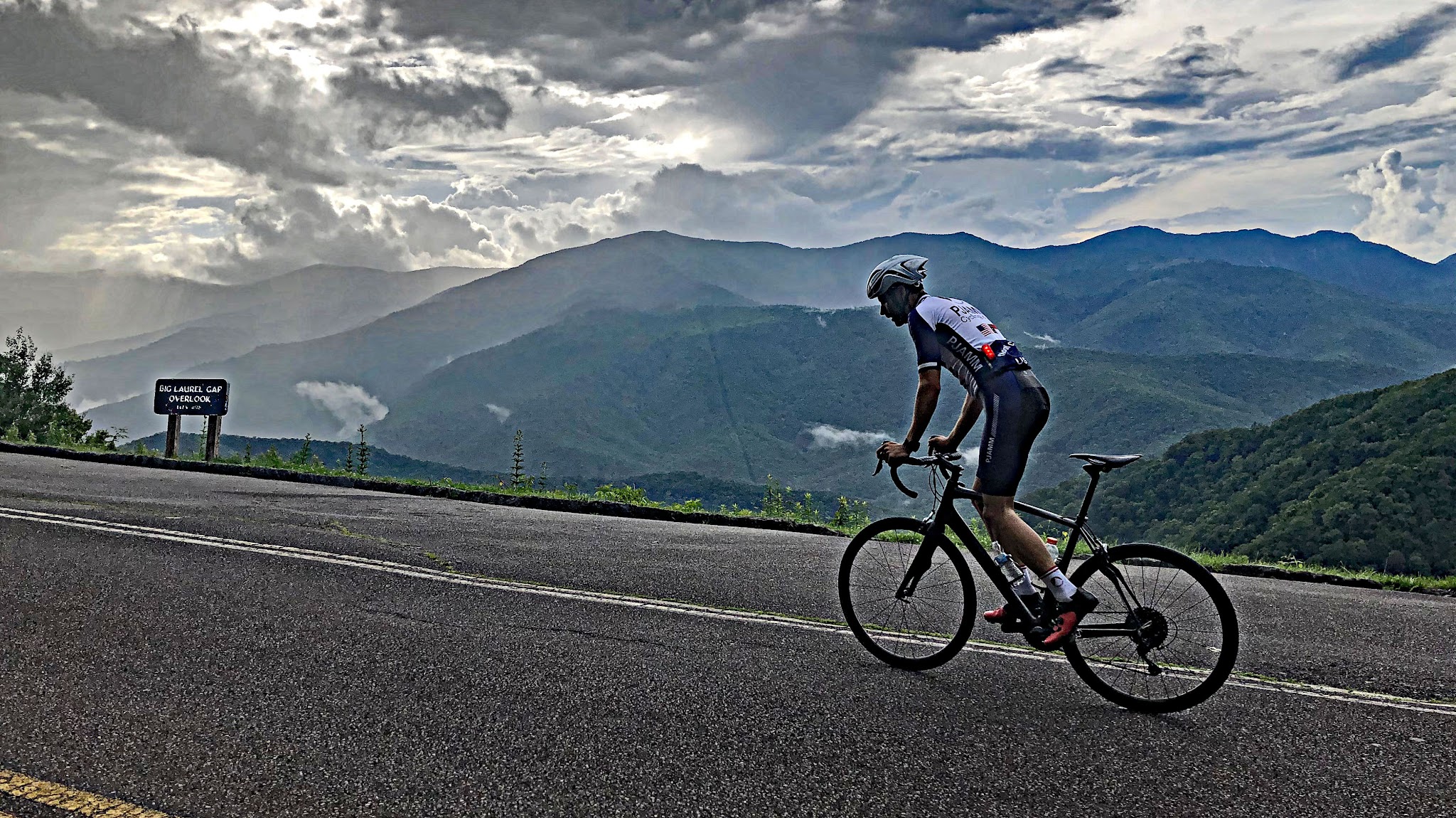 Climbing Mt. Michell by bike - cyclist standing on bike while climbing, road, Blue Ridge Mountains in background