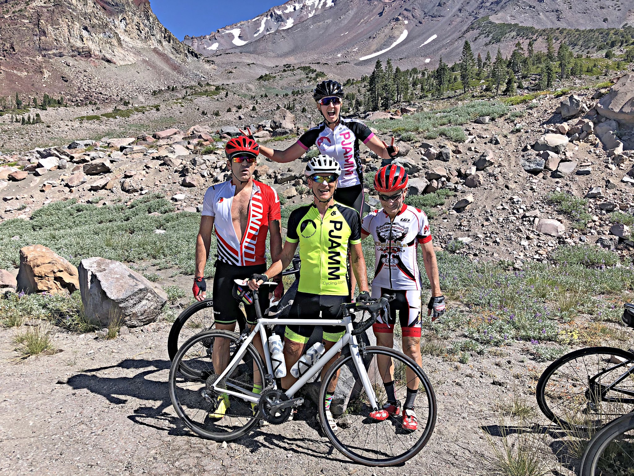 Four PJAMM Cyclists smile with bikes at top of Mt. Shasta road bike climb