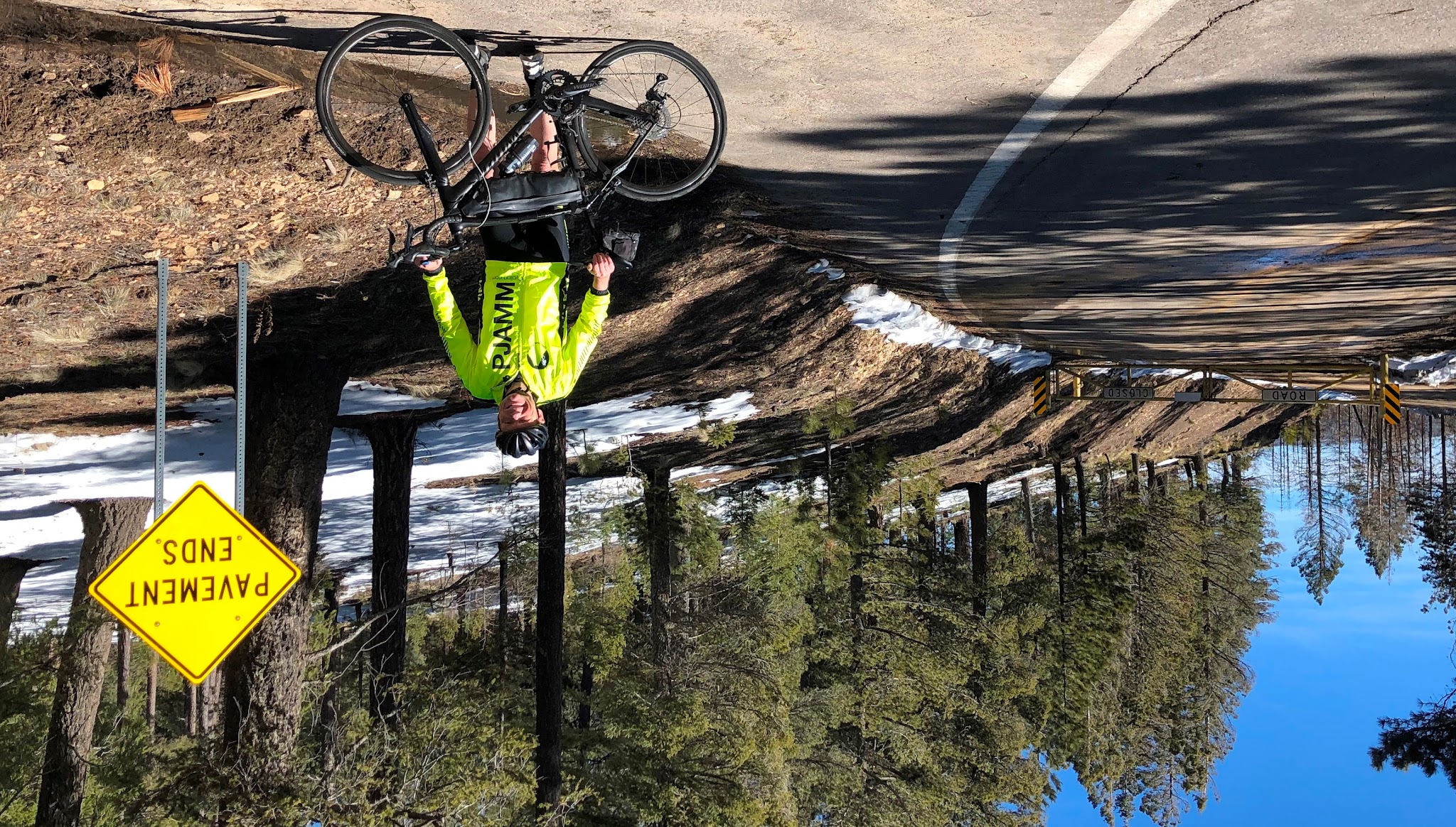 Arizona top bike climbs - End of Mt. Graham bicycle ride - cyclist, bicycle and road Pavement Ends sign.