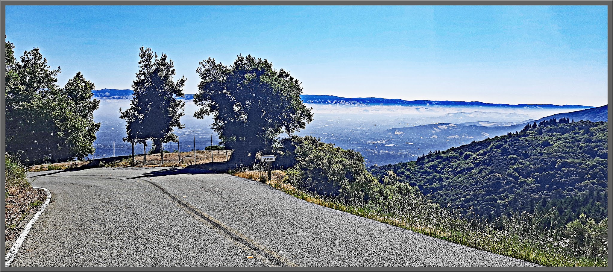 Cycling Bohlman On Orbit - view looking down hill from paved road on hillside, fog rolling in on horizon