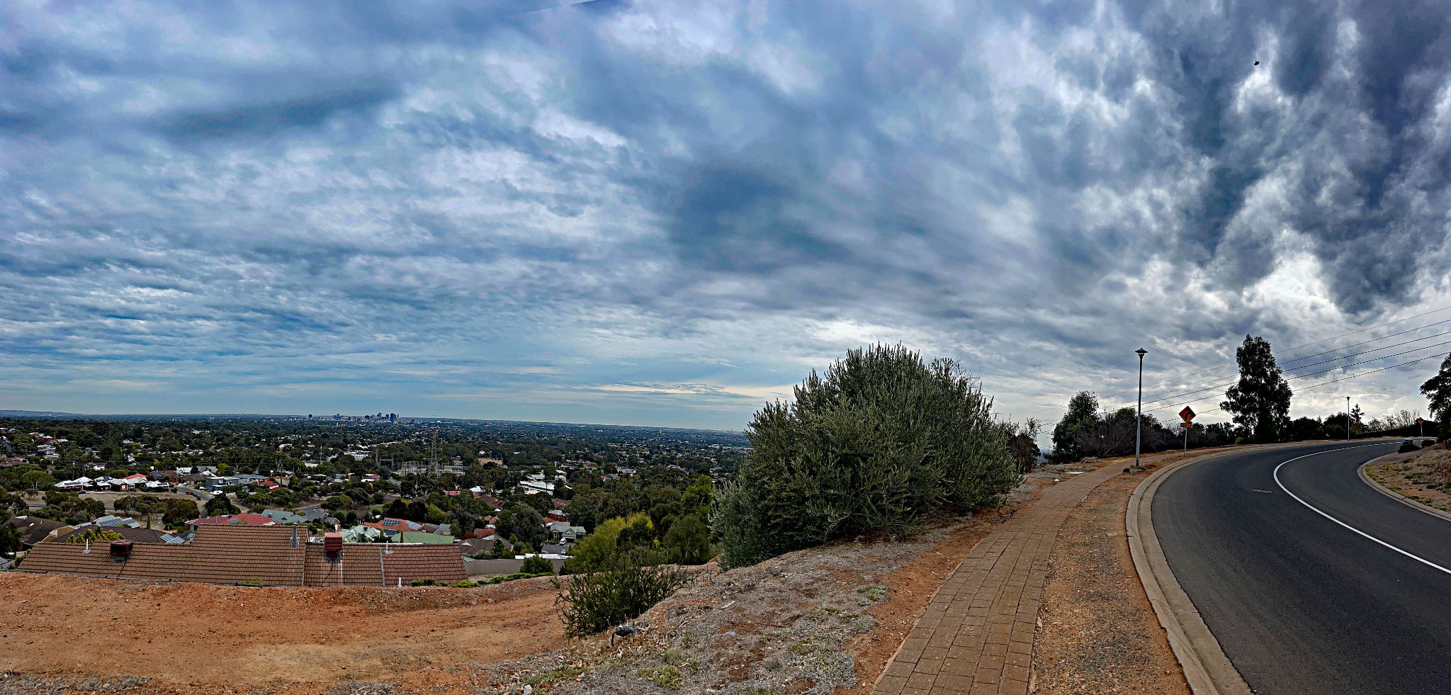 Cycling Coach House Drive and Woodland Way, South Australia two-lane roadway overlooking town below, gorgeous cloud cover in sky