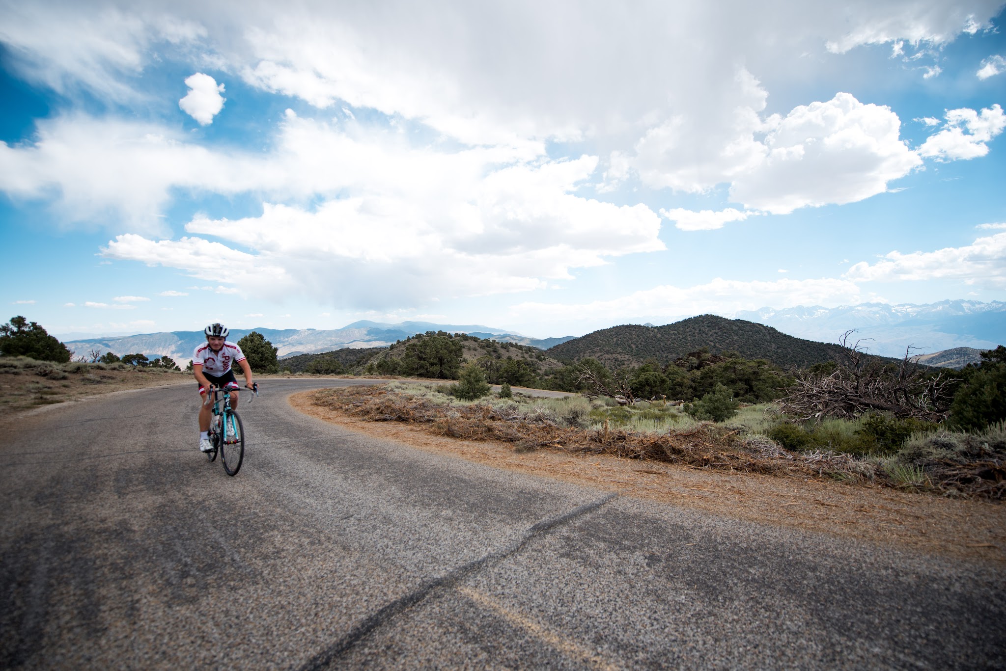 White Mountain Peak from Big Pine, California - cyclist rides on roadway, high desert landscape, blue sky and white clouds in background