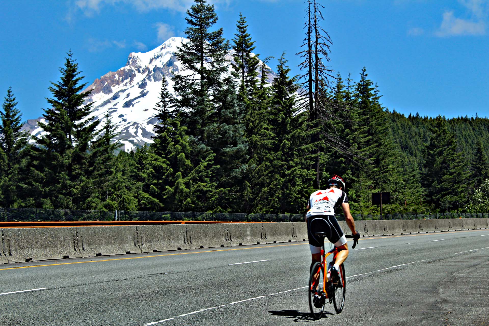 PJAMM Cyclist rides on shoulder of highway road, Snow capped Mt. Hood in the distance