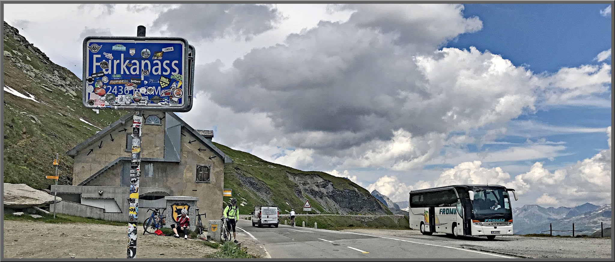 Cycling Furkapass, Realp, Switzerland - sticker covered sign for Furkapass, tour buss, cyclists