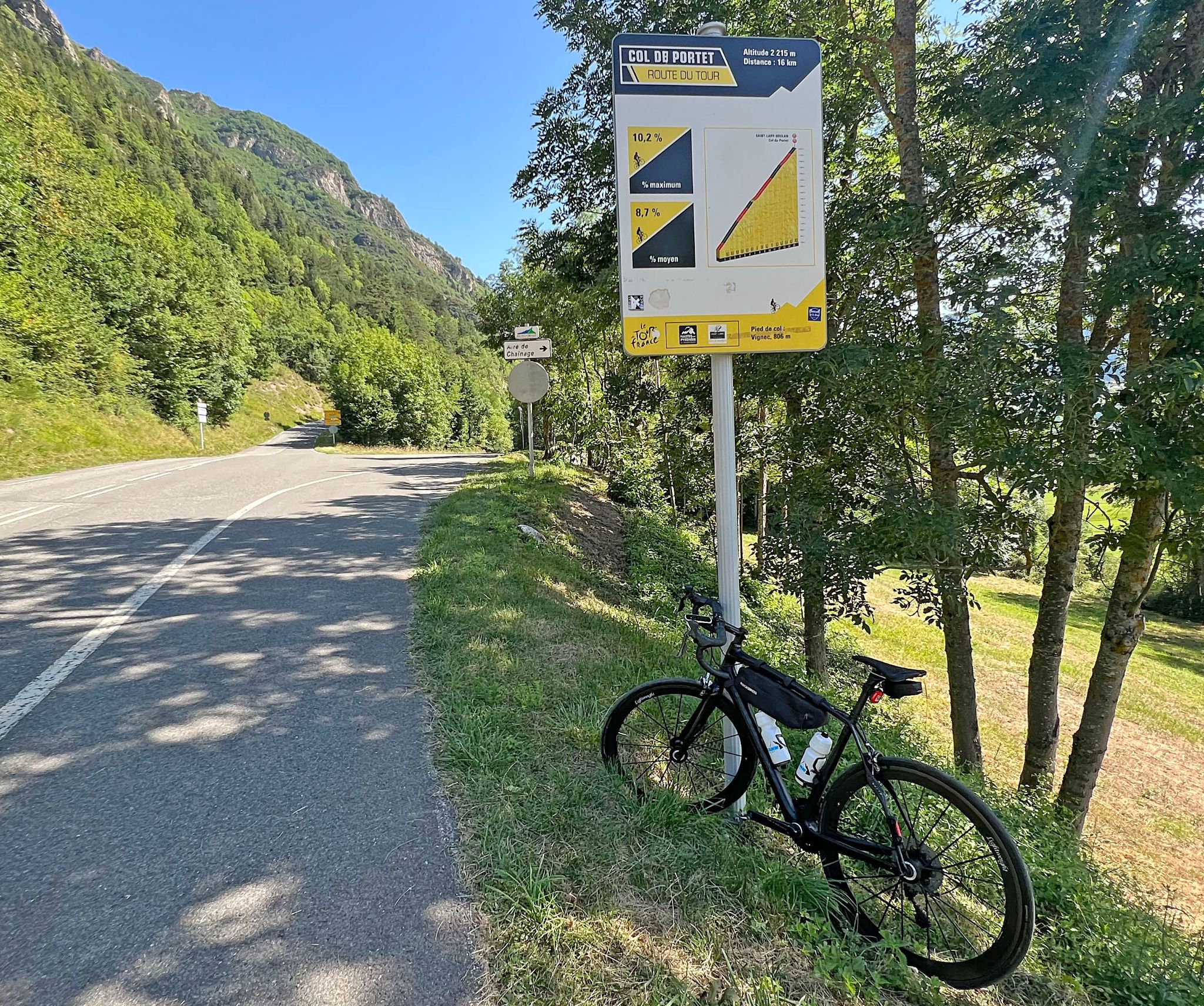 Cycling Col de Portet bike parked on road sign next to Tour de France sign