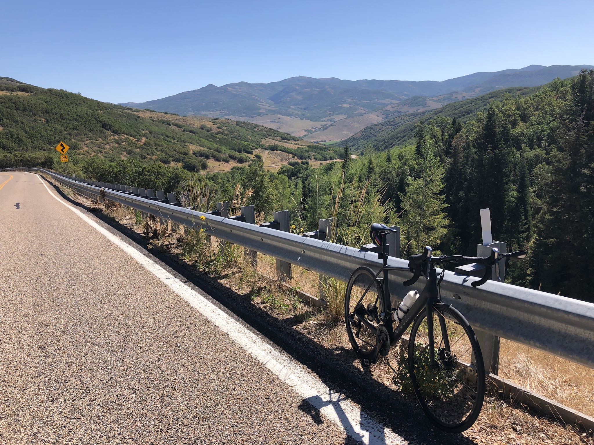 Bike climb Big Mountain Summit East - bike leaning against guard rail with with mountains in background. 