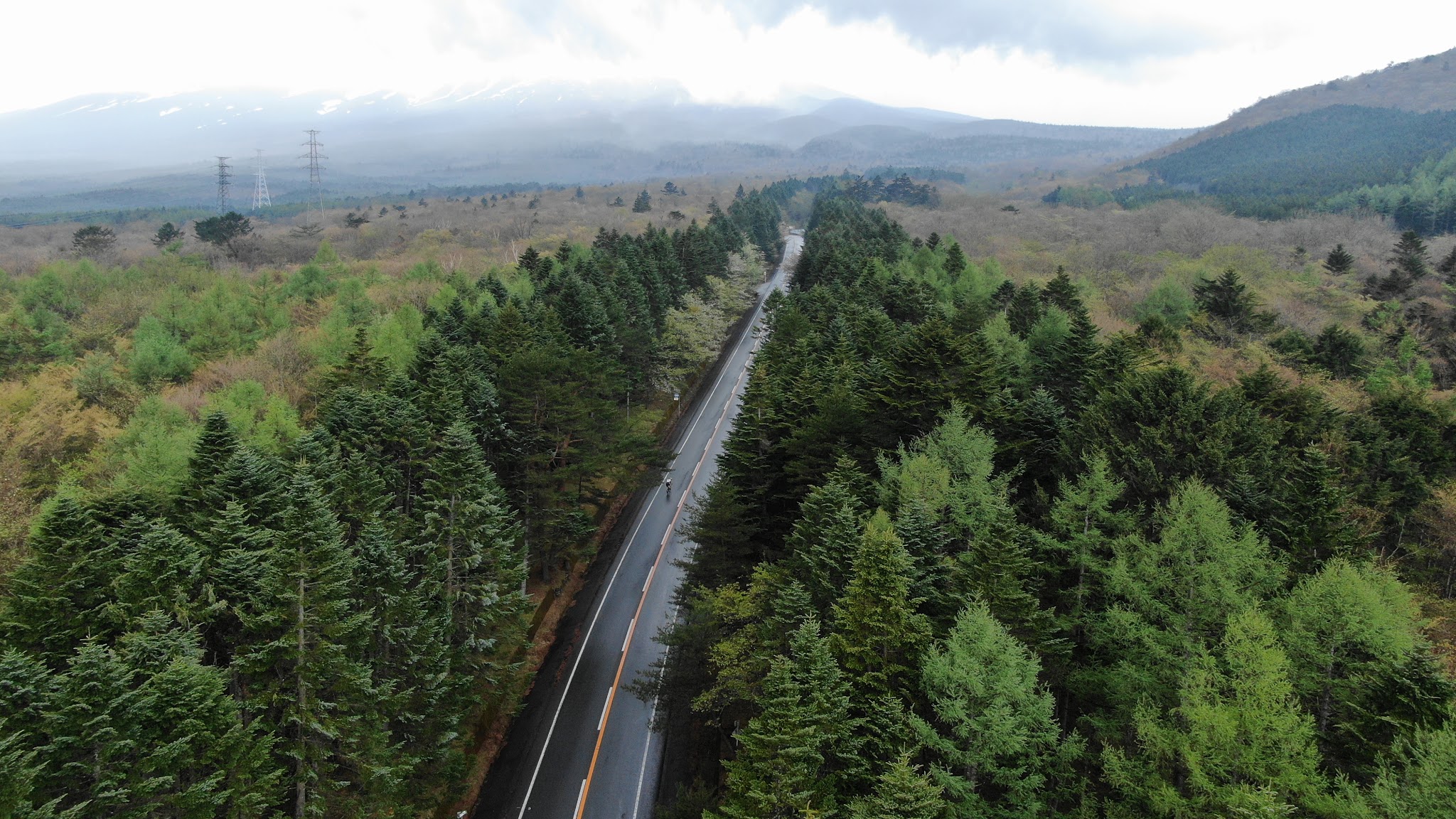 Climbing Mt. Fuji Azami Line by bike - aerial drone photo of roadway and cyclist surrounded by forest