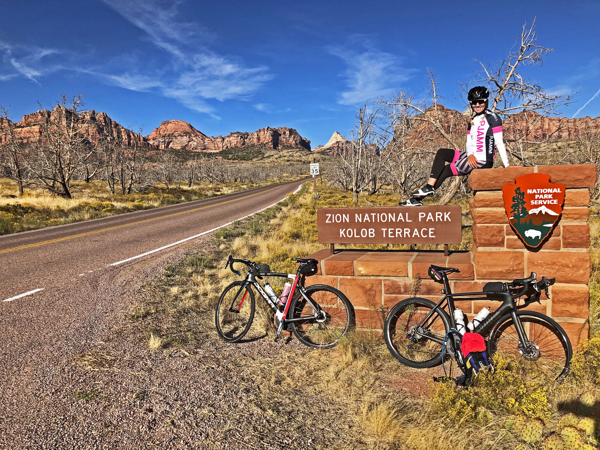 Climbing Kolob Terrace by bike - cyclist at Zion National Park Sign with bike