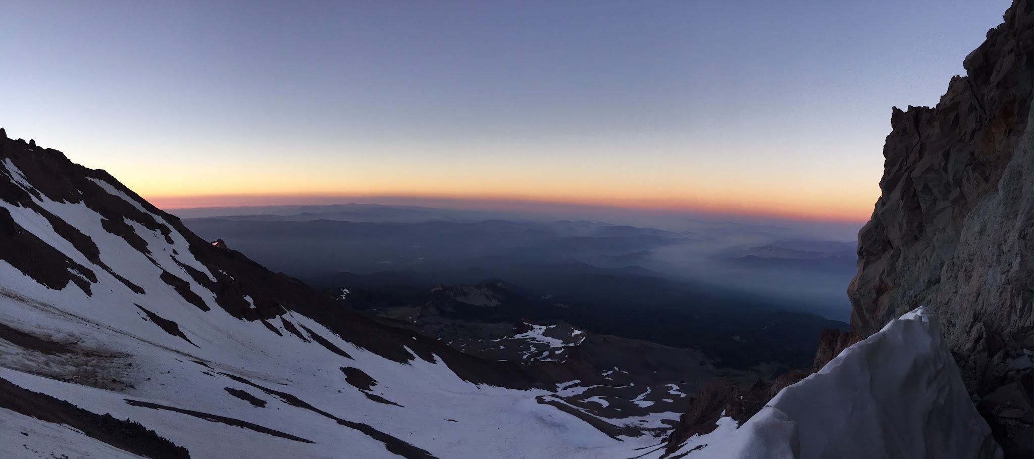 panoramic view looking down from Mt. Shasta summit at sunrise