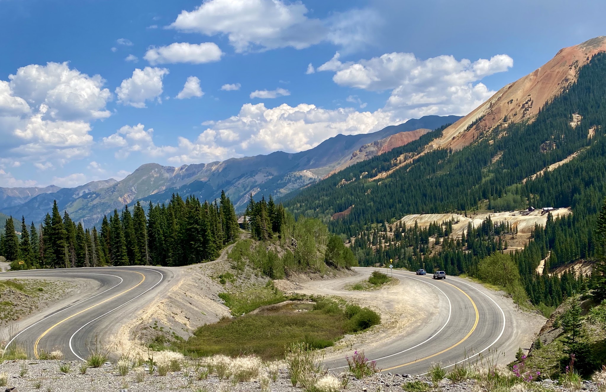 Cycling Red Mountain, Ouray, Colorado - large U curve in two-lane roadway, mountains in background