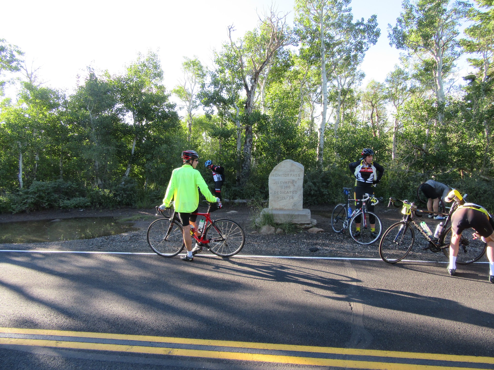 Cyclists stand with bikes next to stone sign on Monitor Pass West portion of Death Ride