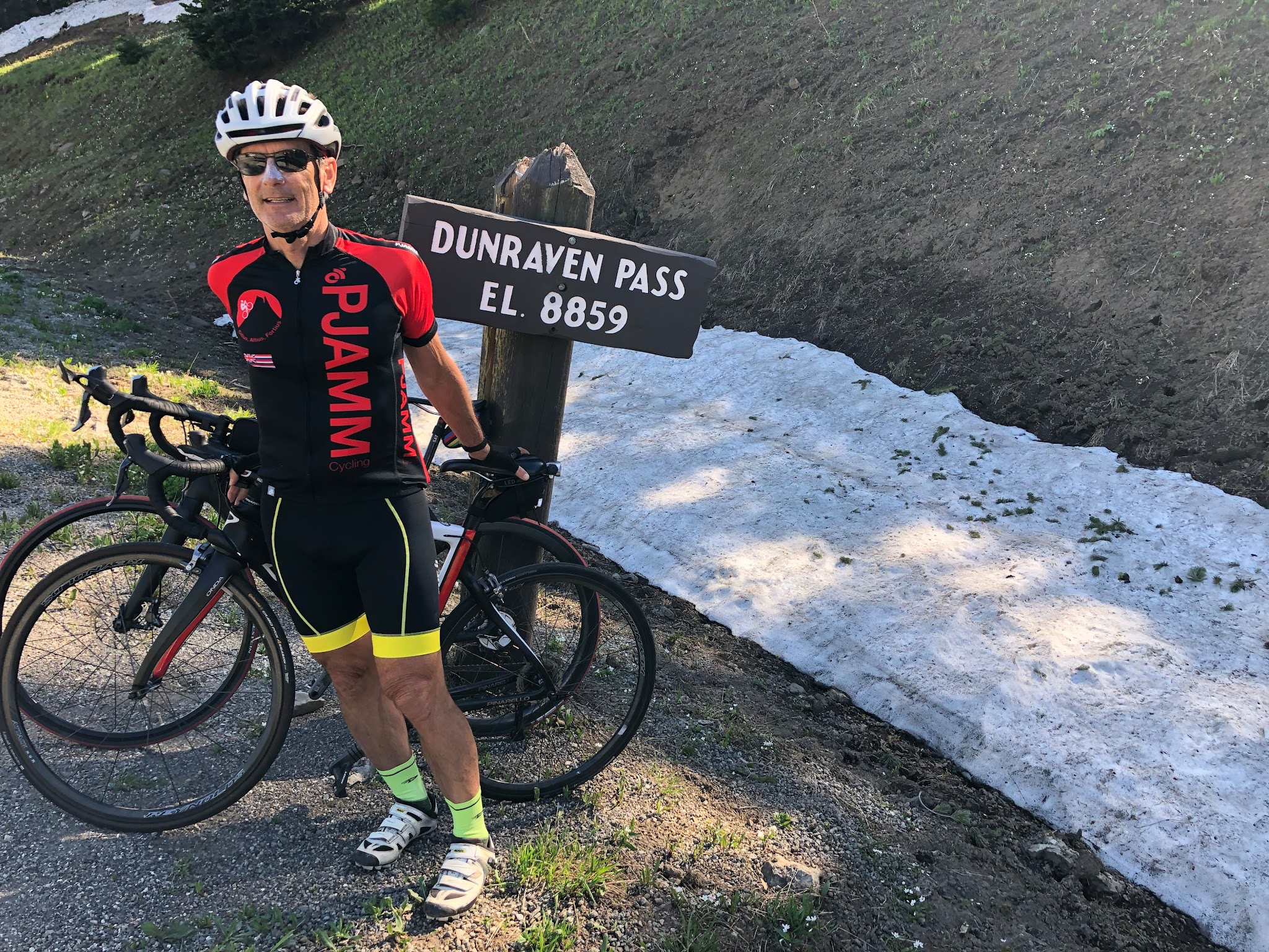 Cycling Yellow Stone National Park - PJAMM Cycling Bruce Hamilton at Dunraven Pass sign with bike