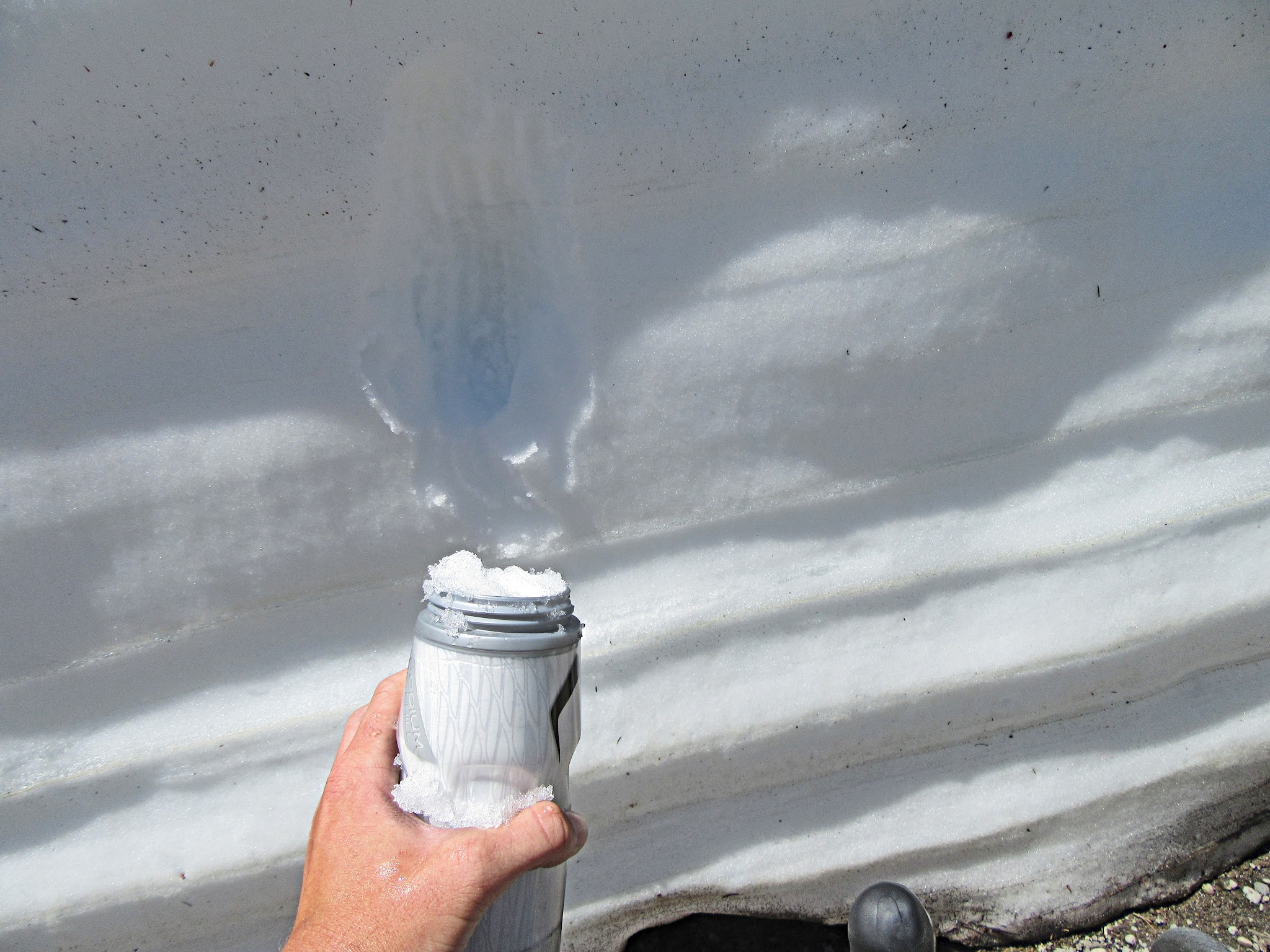 Cycling Mt. Lassen North, California - filling up water bottle by scraping it against snow wall, water bottle filled with snow