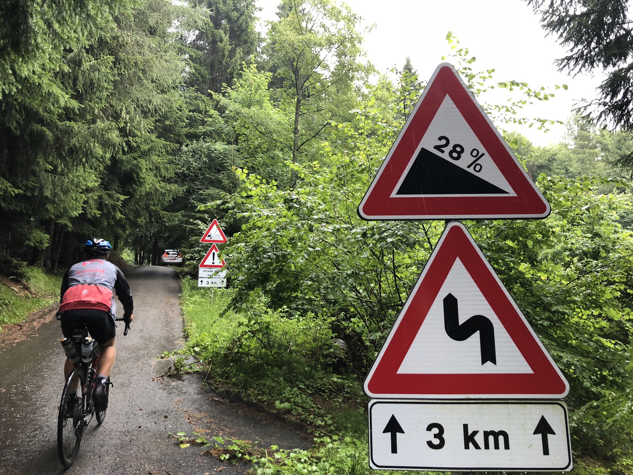 Top bike climbs in Europe  - Bicyclist riding past 28% road sign on Passo della Forcella