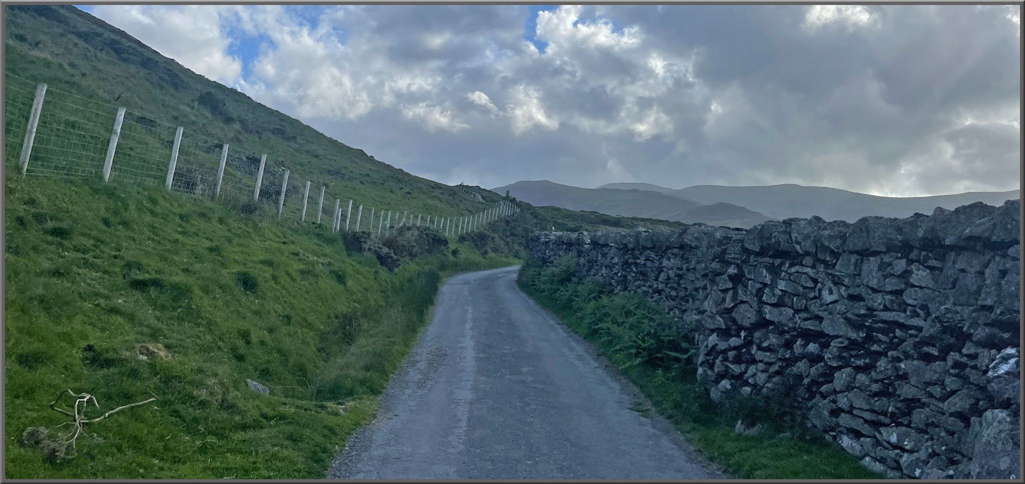 one lane gravel roadway bordered by stone wall
